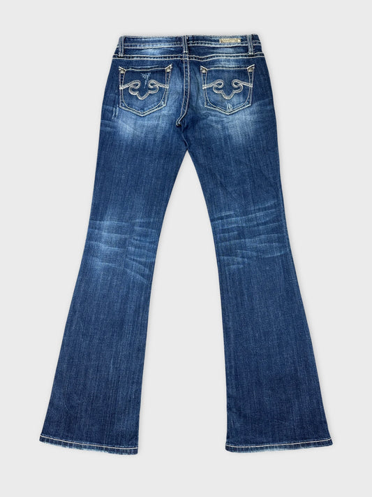 Back view of long blue jeans featuring decorative stitched pockets.
