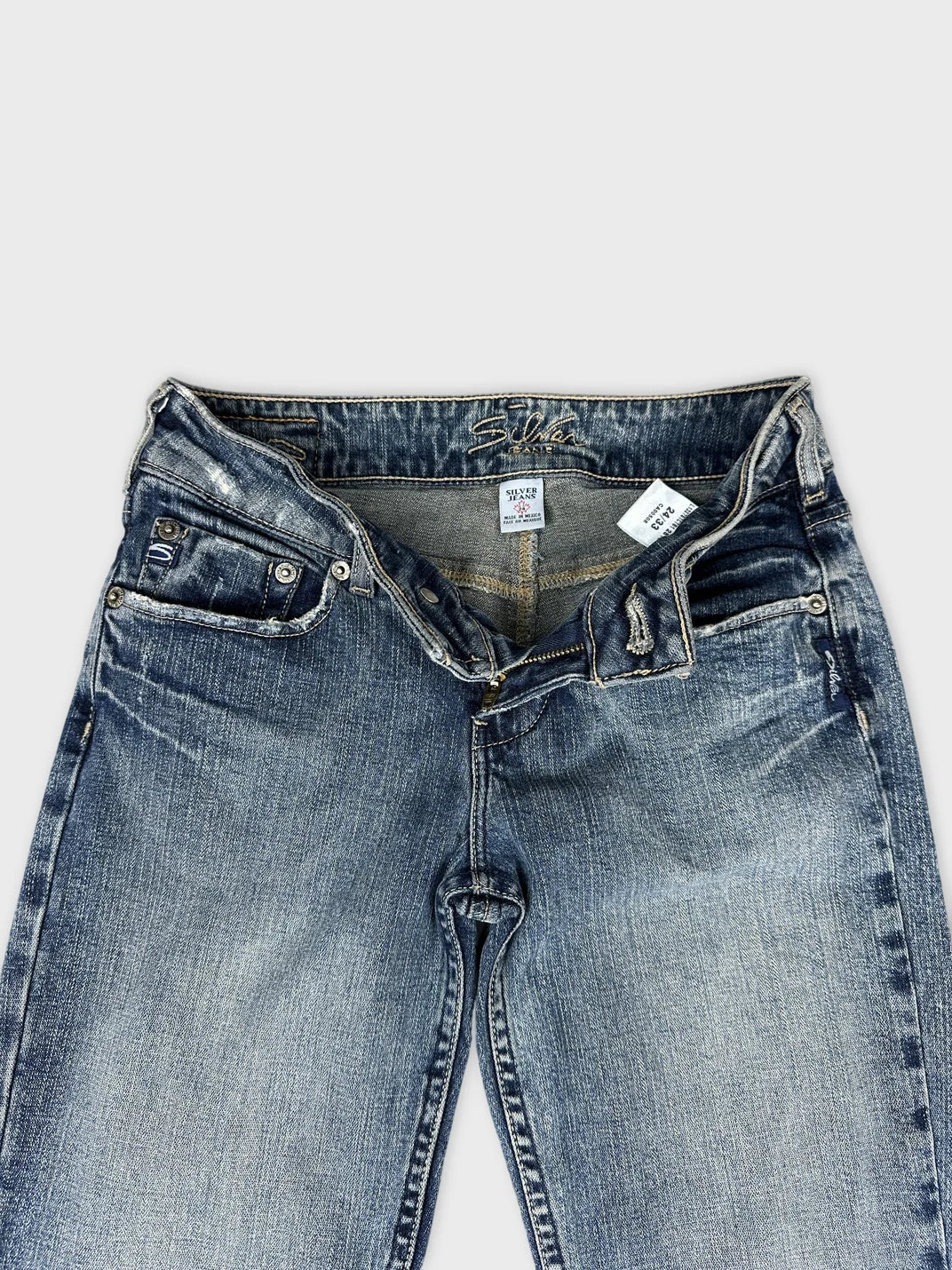 Detail view of long jeans in faded blue with zipper and pockets.