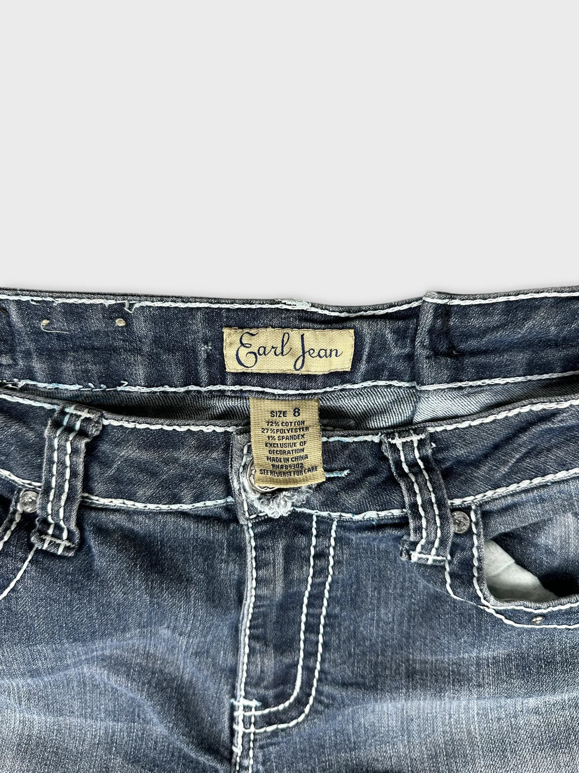 Detail view of dark blue long jeans featuring contrast stitching and button closure.