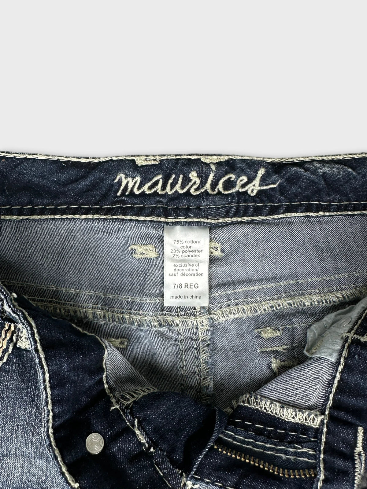 Detail view of dark blue jeans showing stitched waistband and label.