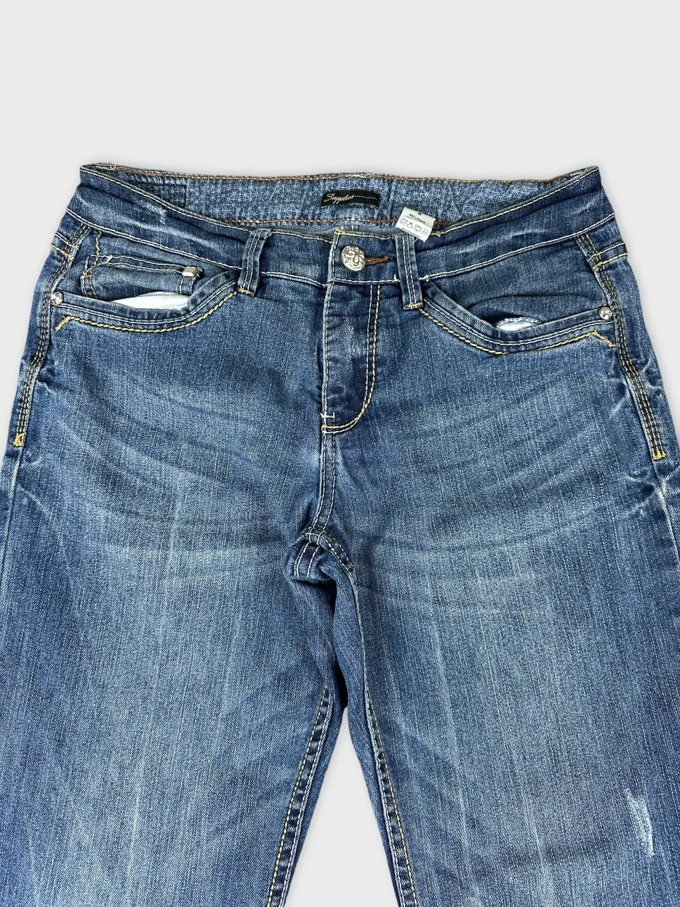 Detail view of women’s long jeans in blue with faded texture.