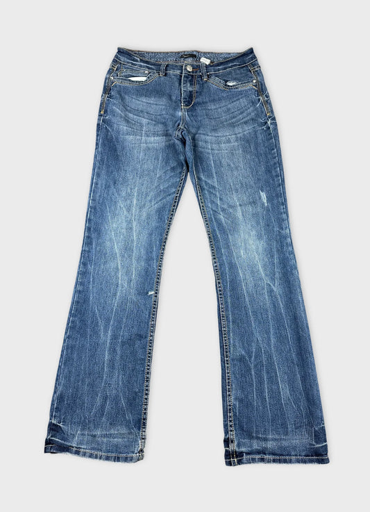 Front view of long blue jeans with slight distressed details.