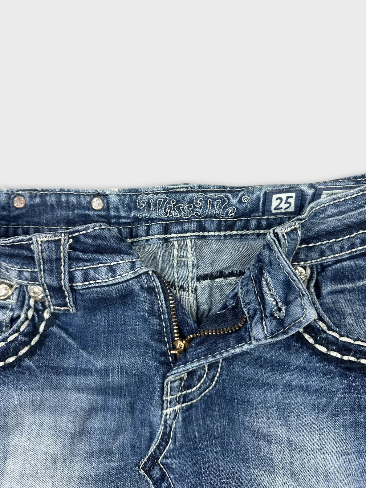 Detail view of a denim mini skirt with distressed blue fabric and a zip closure.