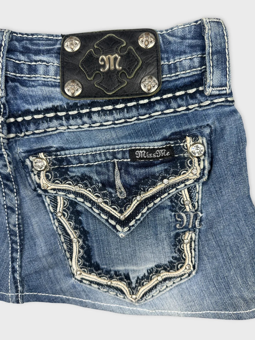Detail view of a denim mini skirt featuring blue color and decorative stitching.