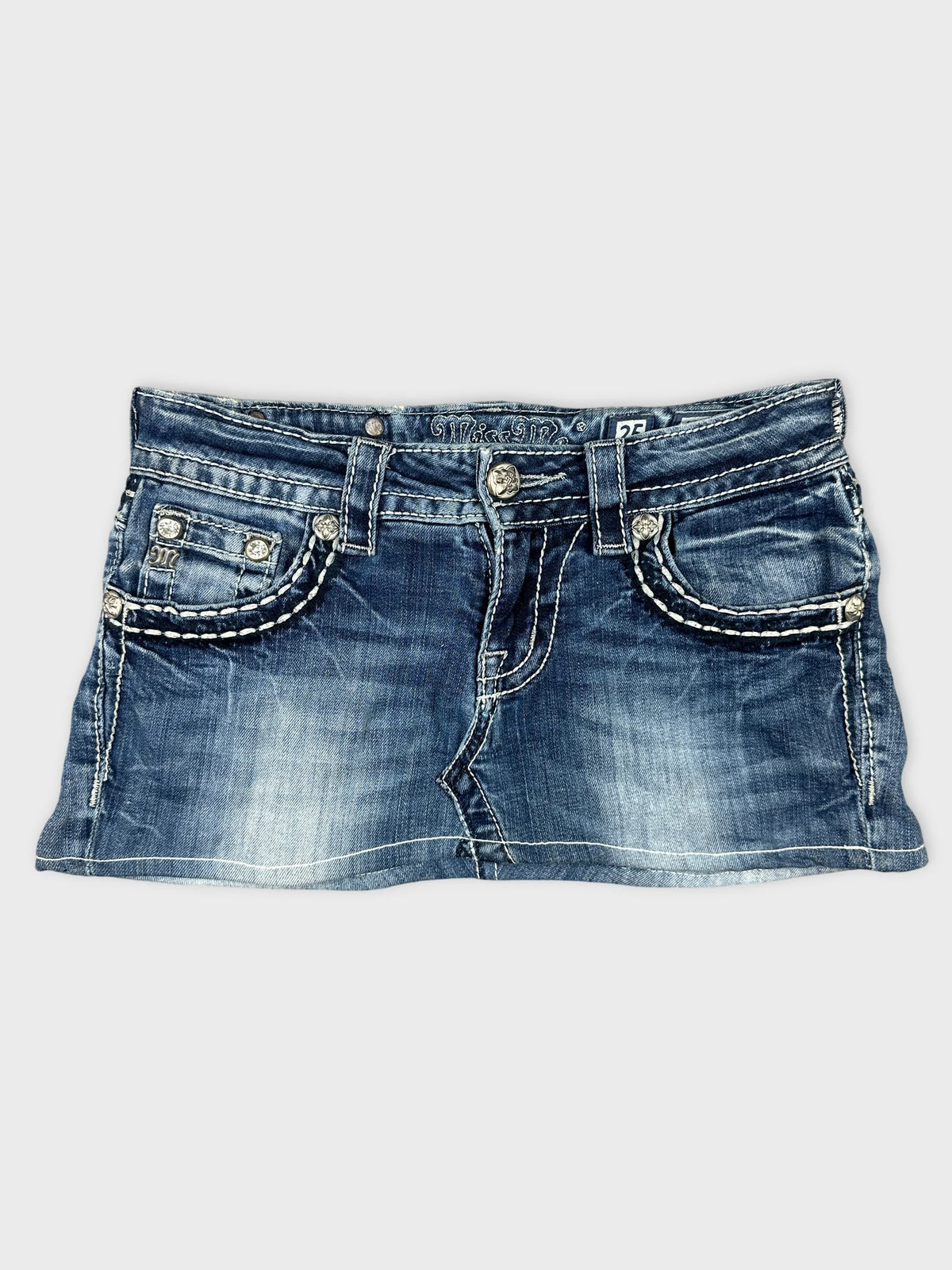Front view of denim mini skirt featuring embellished pockets and white stitching.
