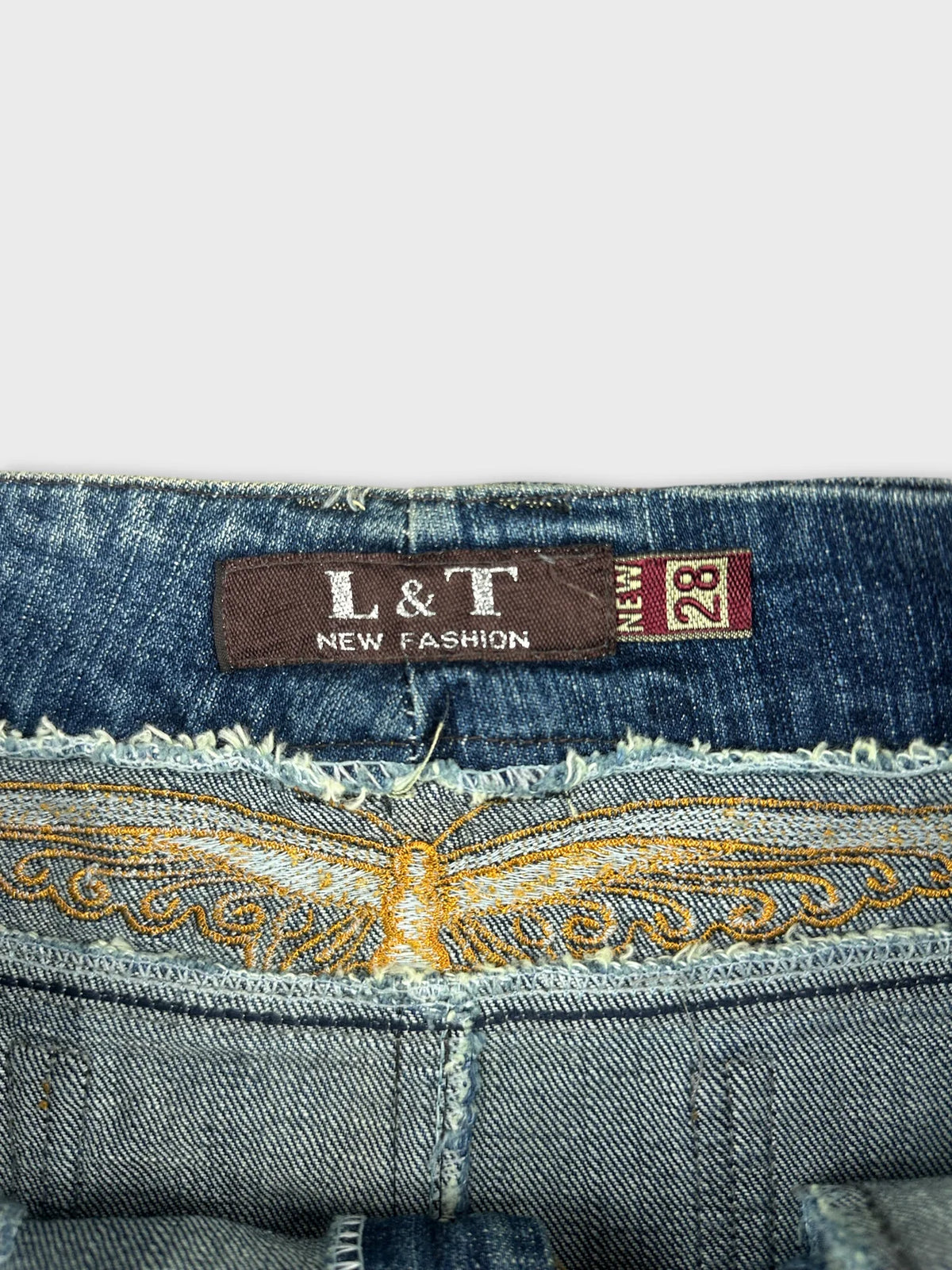 Detail view of a blue denim miniskirt with intricate embroidery on the waistband.