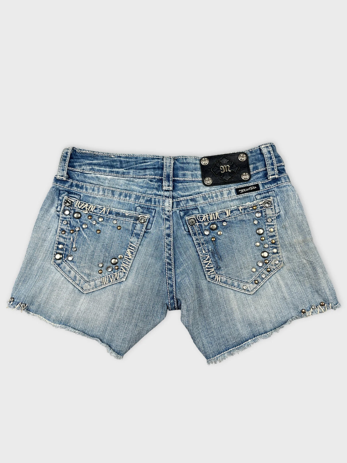 Back view of denim shorts with studded detailing and a frayed hem
