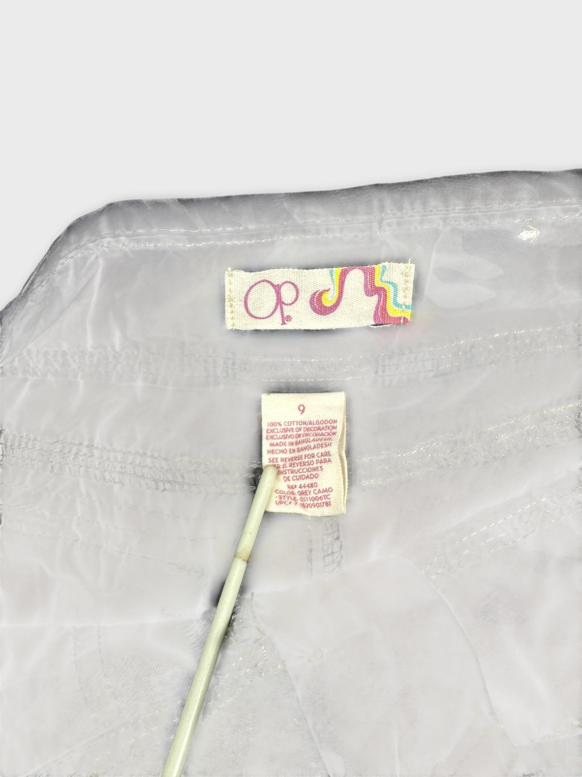 Detail view of white women shorts with a colorful label and stitching.