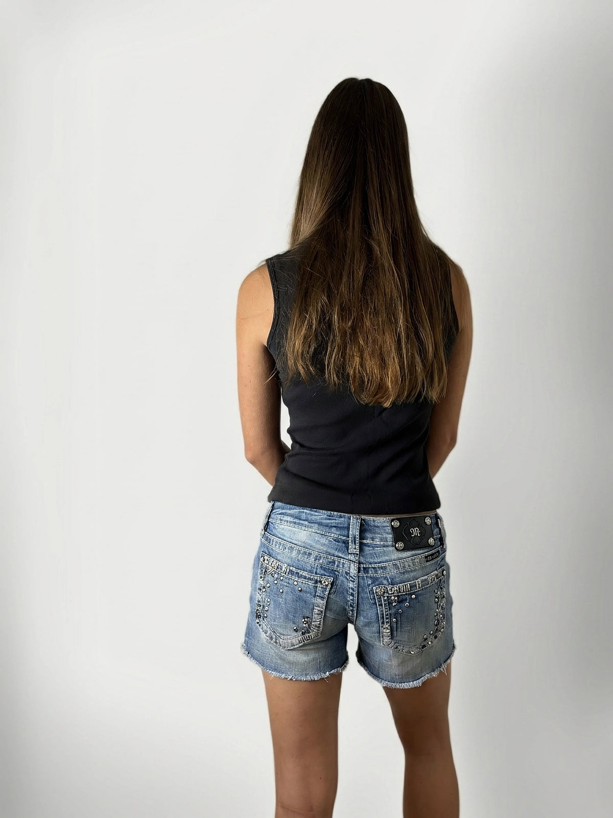 Back view of women's denim shorts in light blue with rhinestone embellishments.