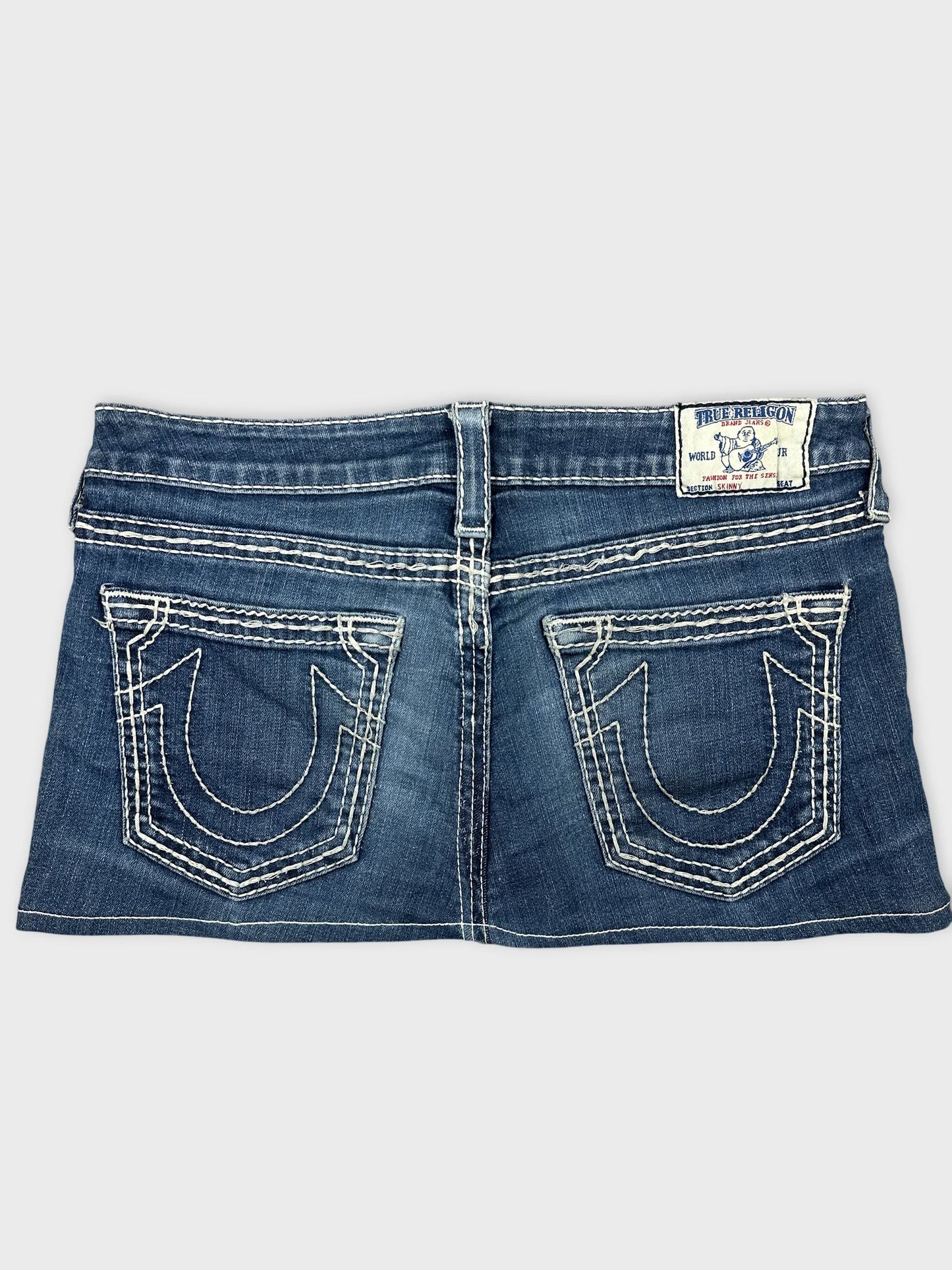 Back view of a denim mini skirt in dark blue with embellished pockets.