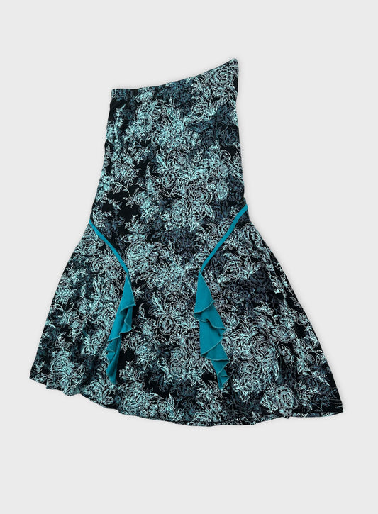 Back view of a black floral print skirt with teal ruffle detailing.