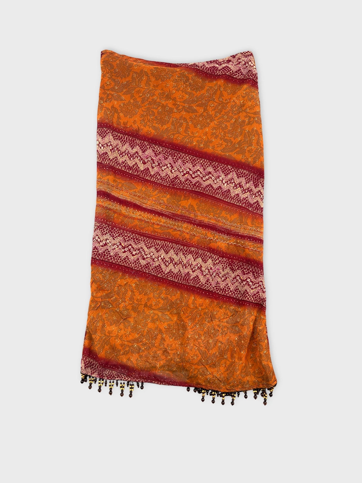 Back view of a vintage orange skirt with intricate red patterned trim.
