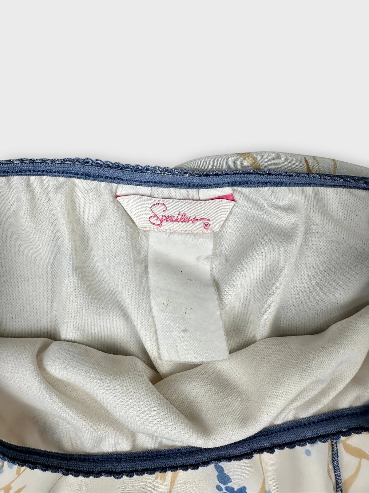 Detail view of a vintage women's skirt featuring a light cream color and decorative trim.