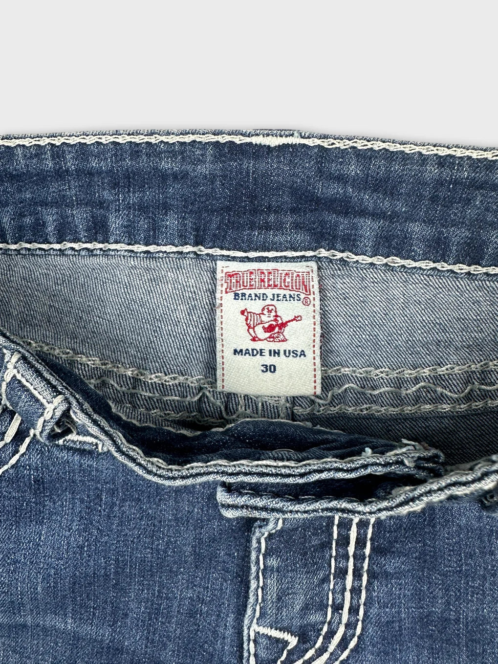 Detail view of blue denim skirt with frayed waistband and contrasting stitching