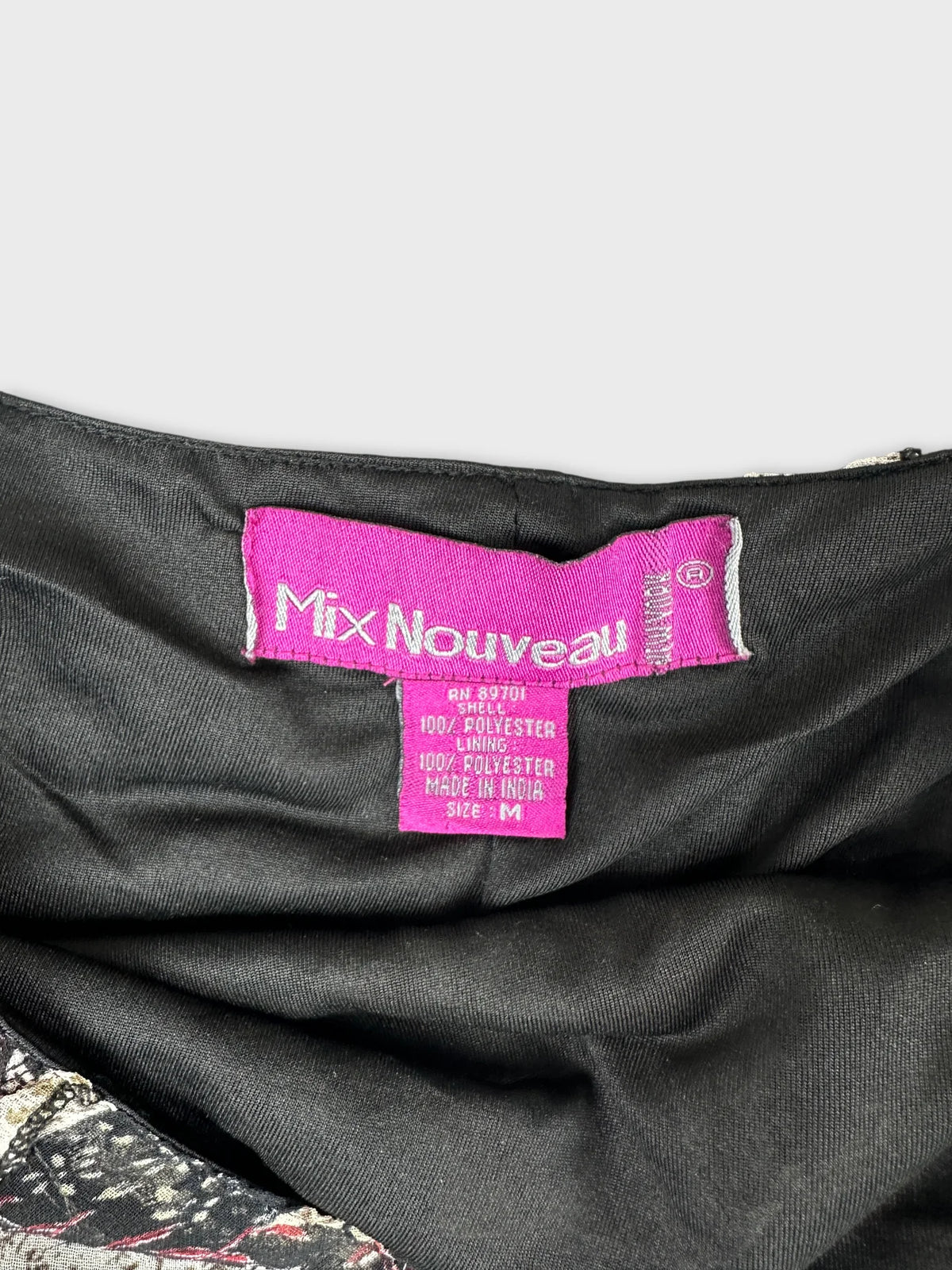 Detail view of a vintage women's skirt with a pink label and black lining.