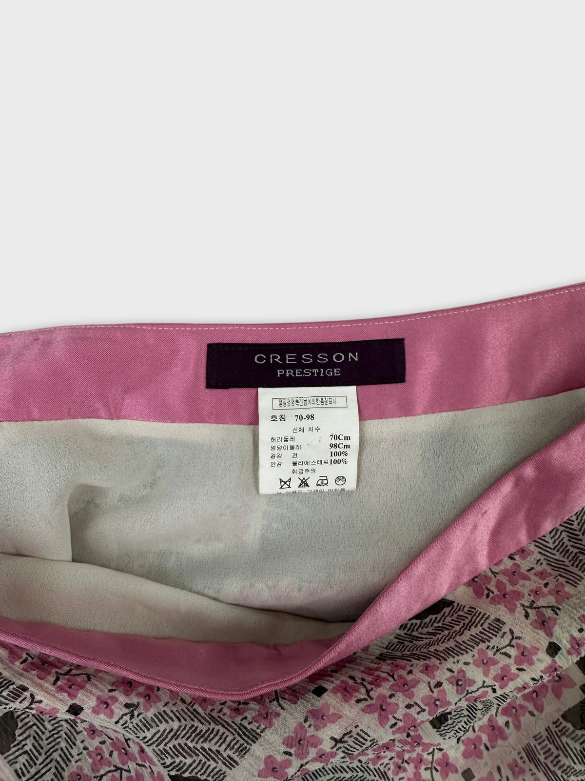 Detail view of a vintage women's skirt with a floral print and pink waistband.