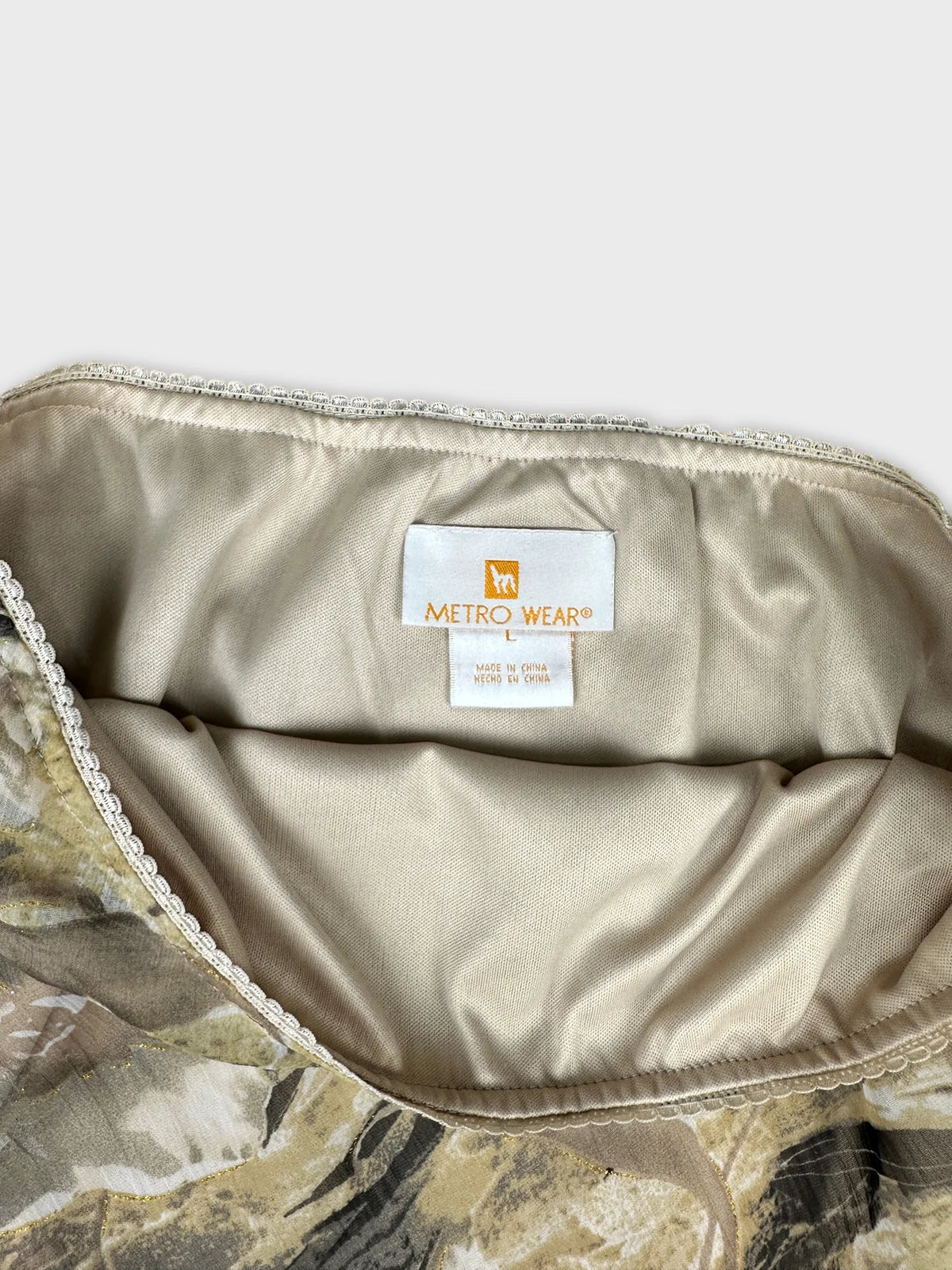 Detail view of a vintage skirt in beige with floral print and lace trim.