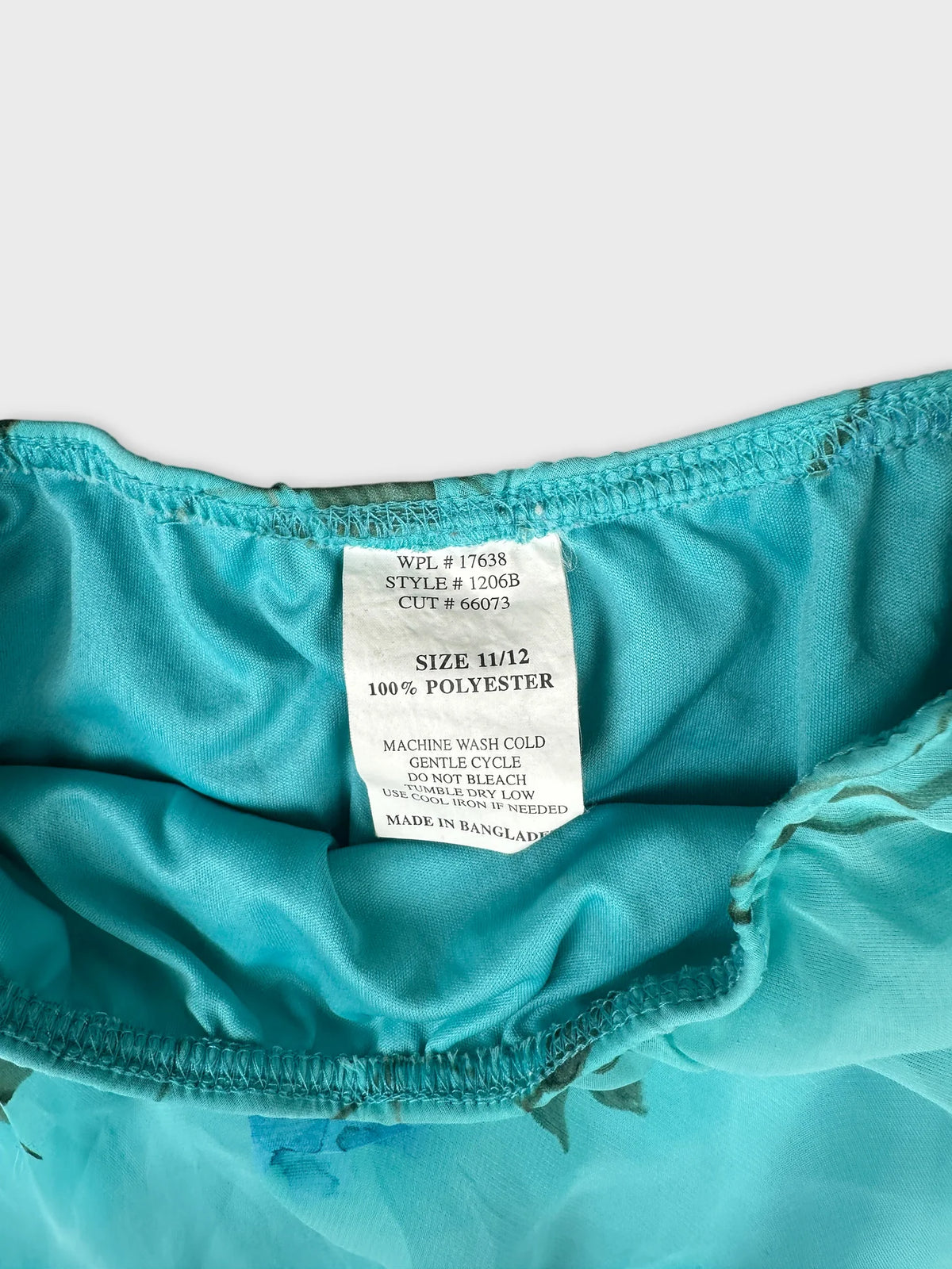 Detail view of a teal skirt with floral print and elastic waistband.
