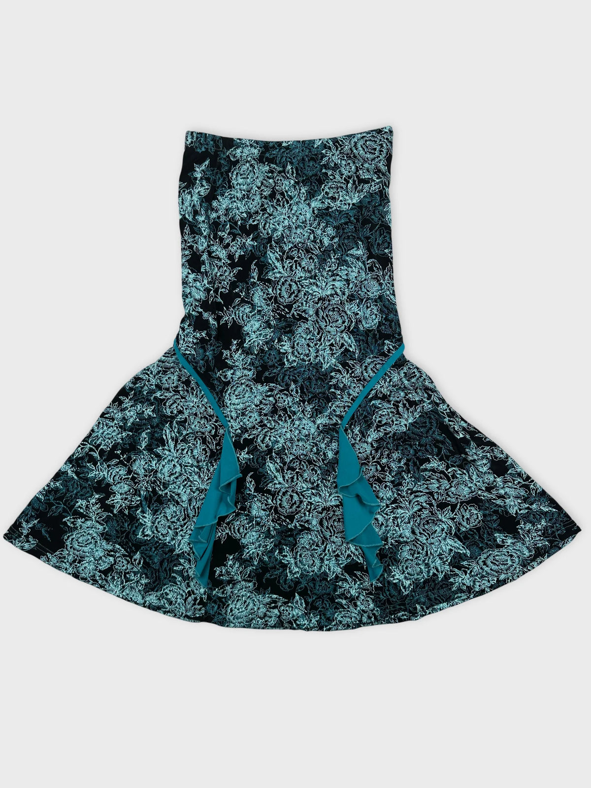 Detail view of a flared black skirt with teal floral pattern and ruffle trim.
