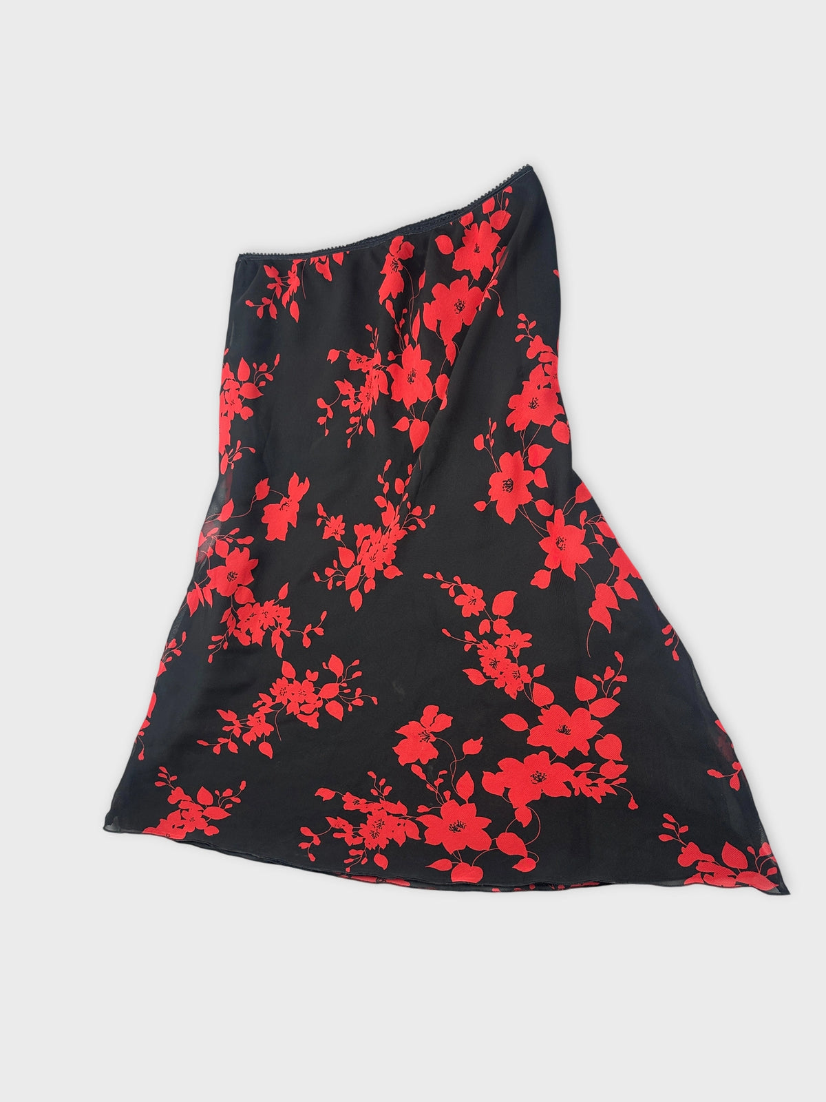 Detail view of a black skirt with red floral pattern.
