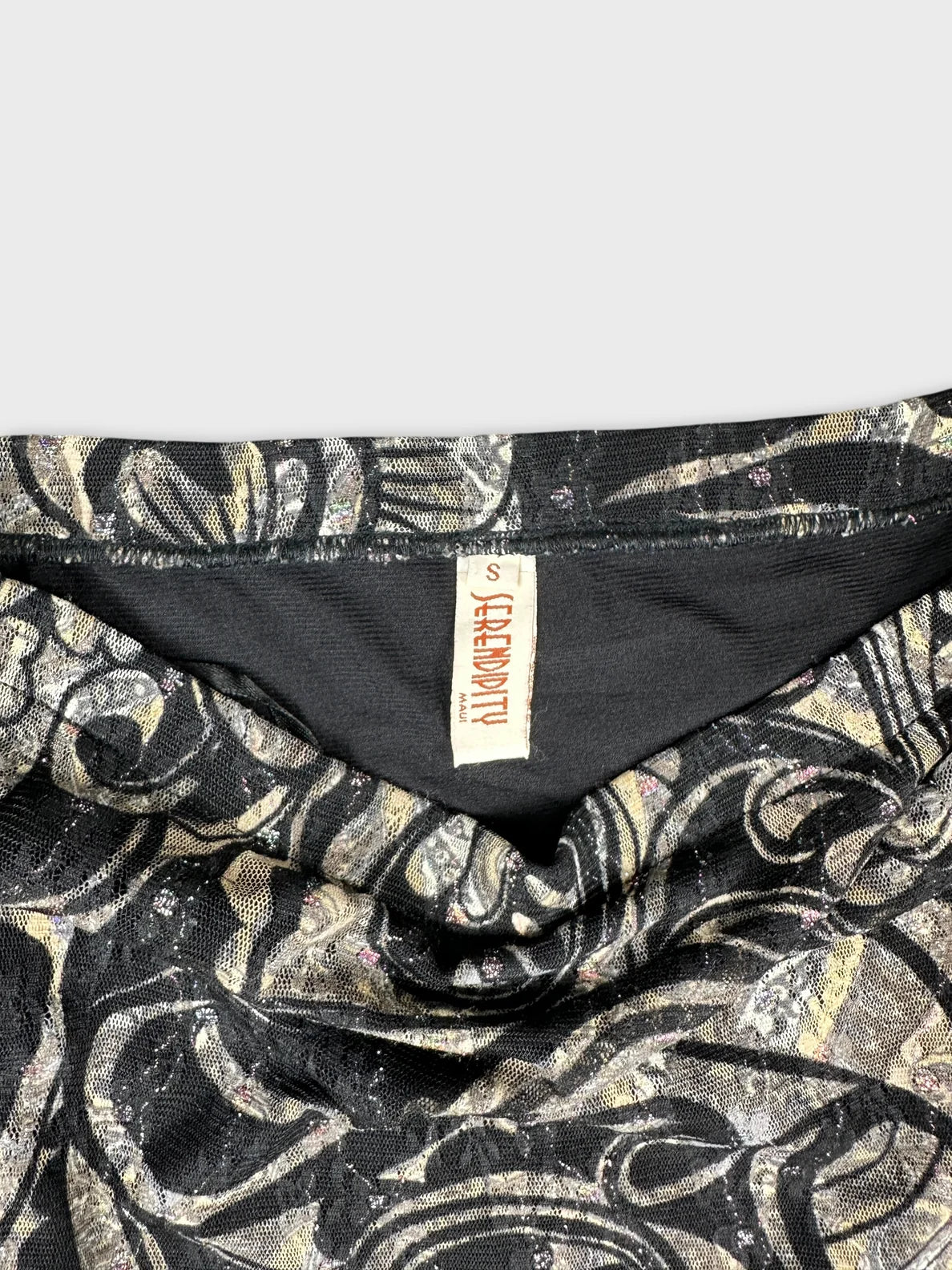 Detail view of a black skirt with a metallic swirl pattern.