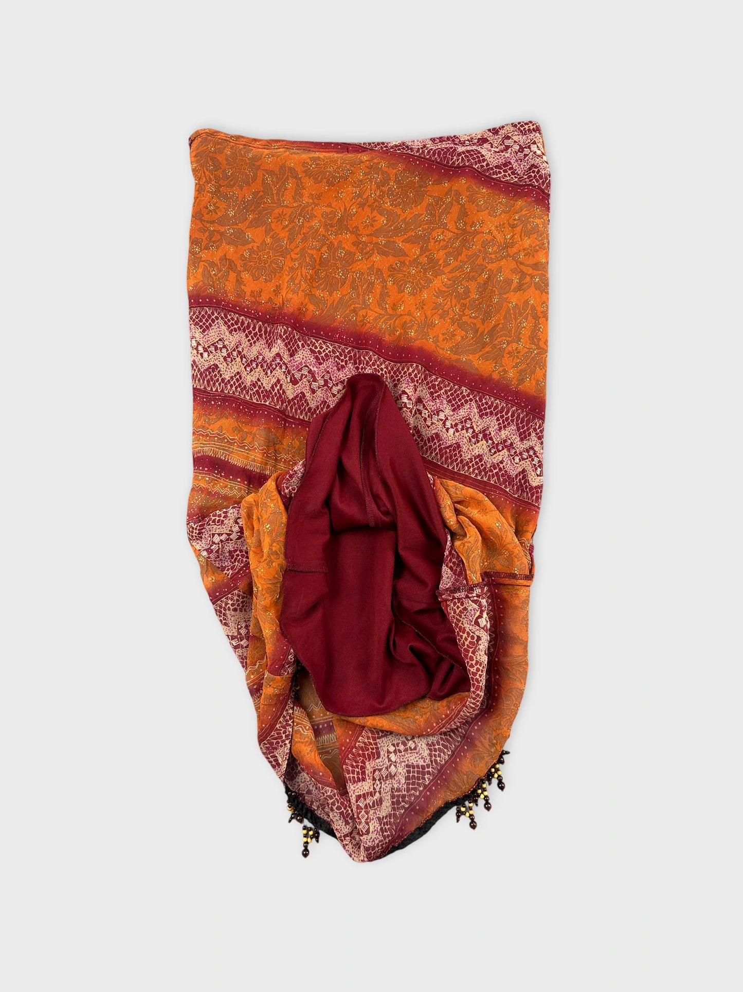 Detail view of a vintage skirt in orange with intricate patterns.