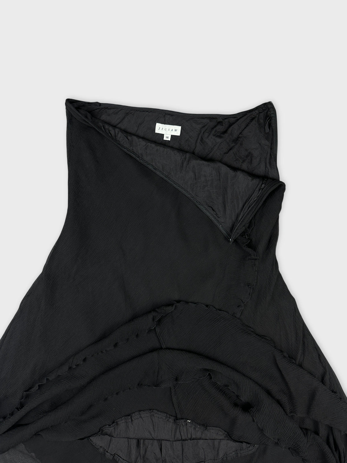 Black skirt detail view showcasing ruffled edges and smooth fabric texture.