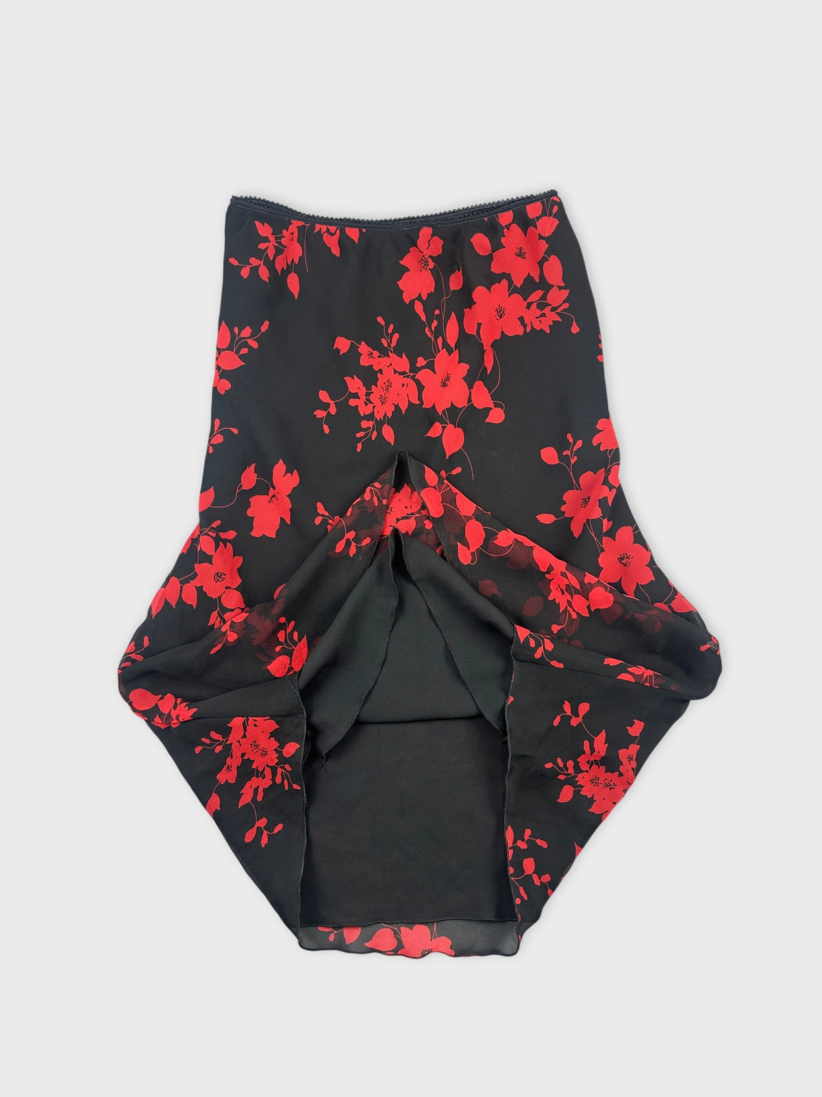 Detail view of a black floral skirt with red flowers.