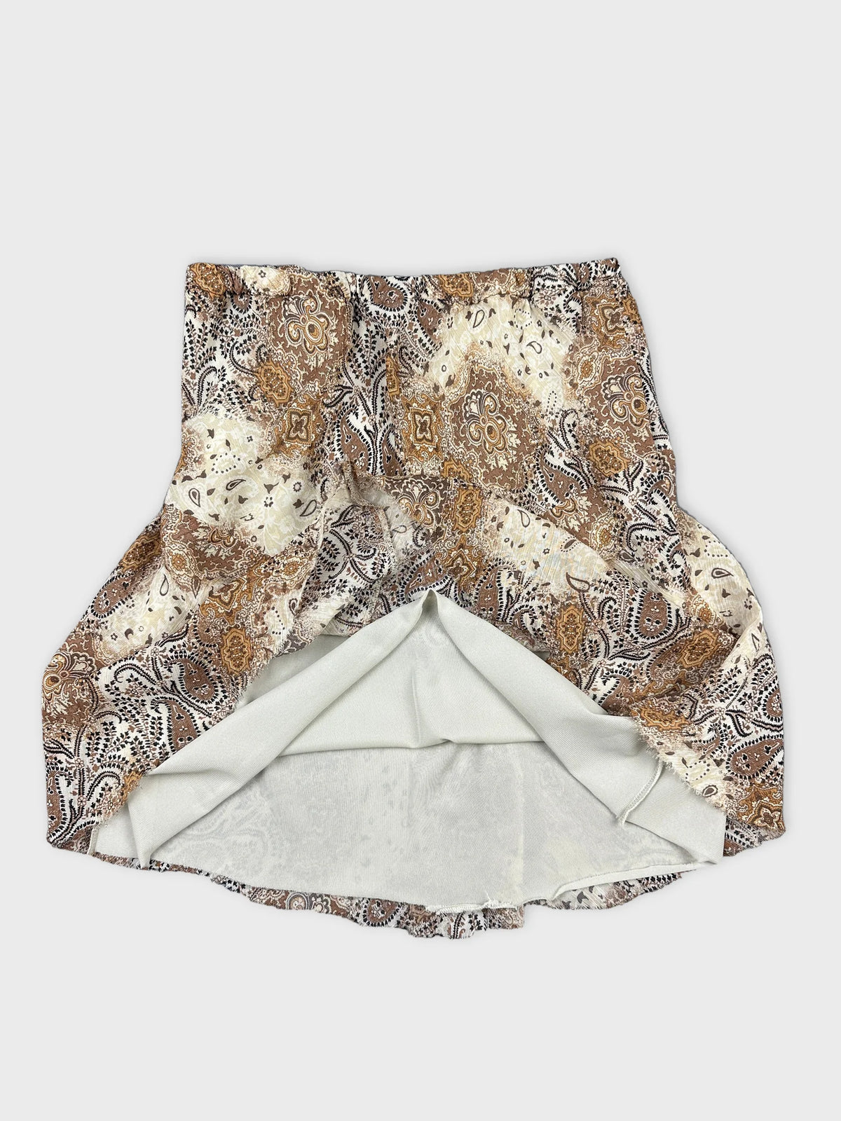 Detail view of a vintage women’s skirt featuring a paisley pattern in brown and cream.