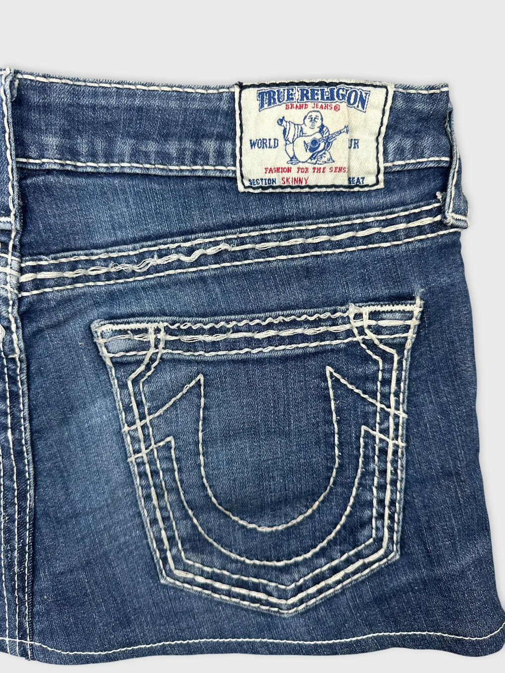 Detail view of a blue denim skirt with intricate back pocket stitching.