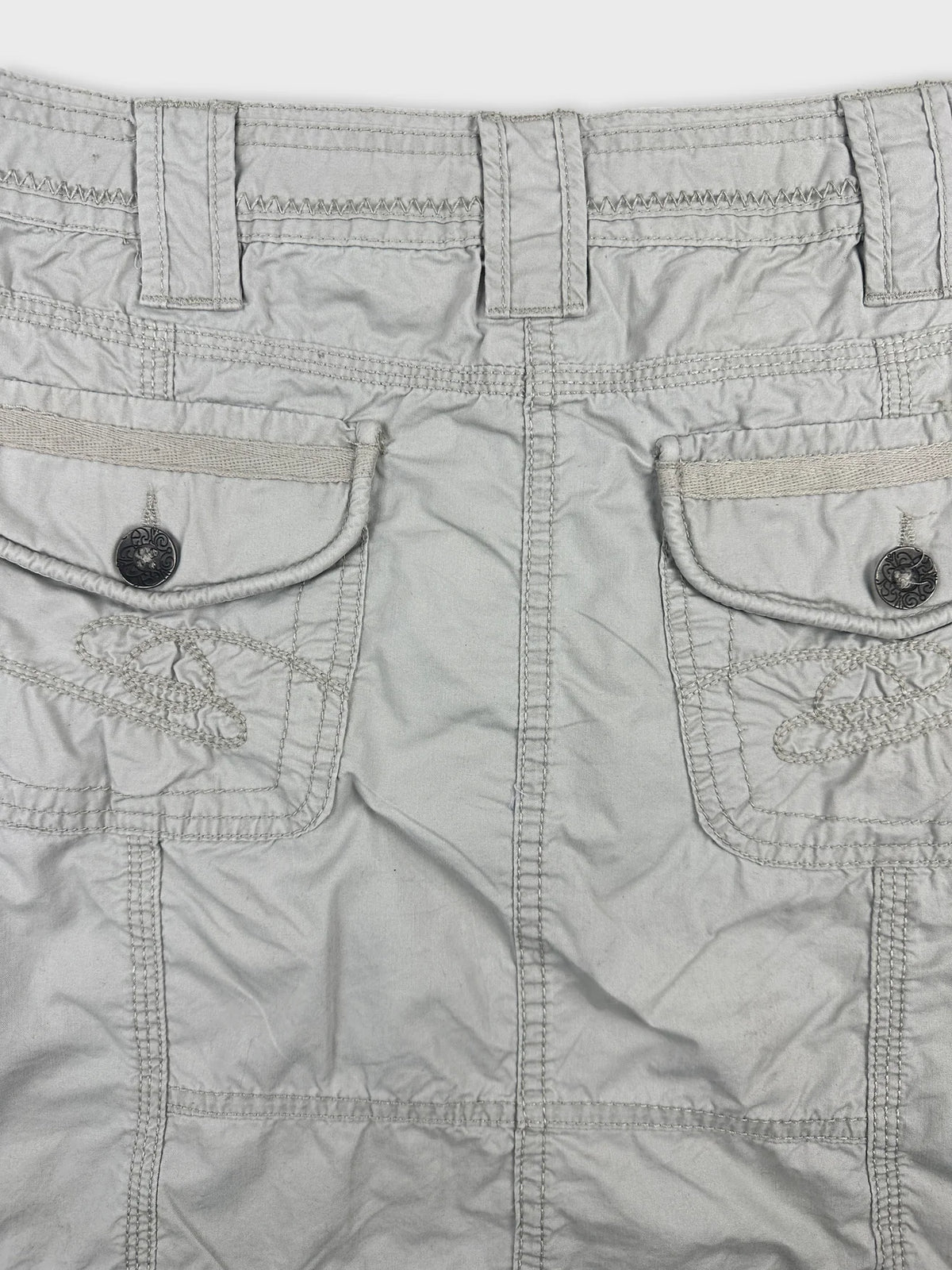 Detail view of a light gray skirt with embroidered pockets.
