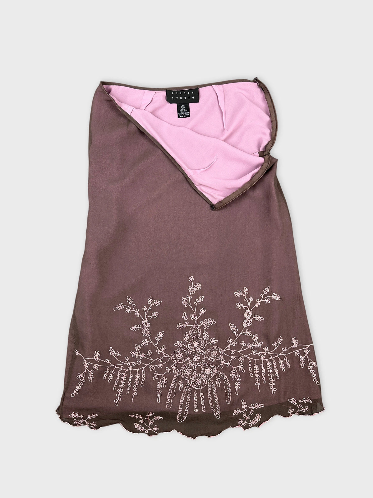 Detail view of a brown skirt featuring floral embroidery on the hem.