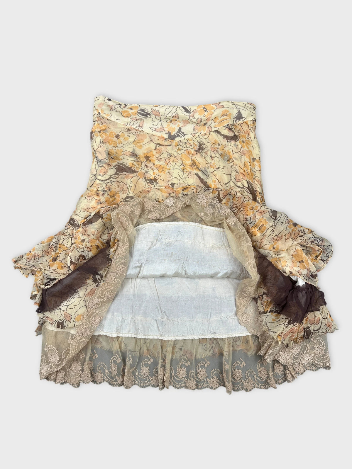 Detail view of a floral vintage skirt in soft beige with lace trim.
