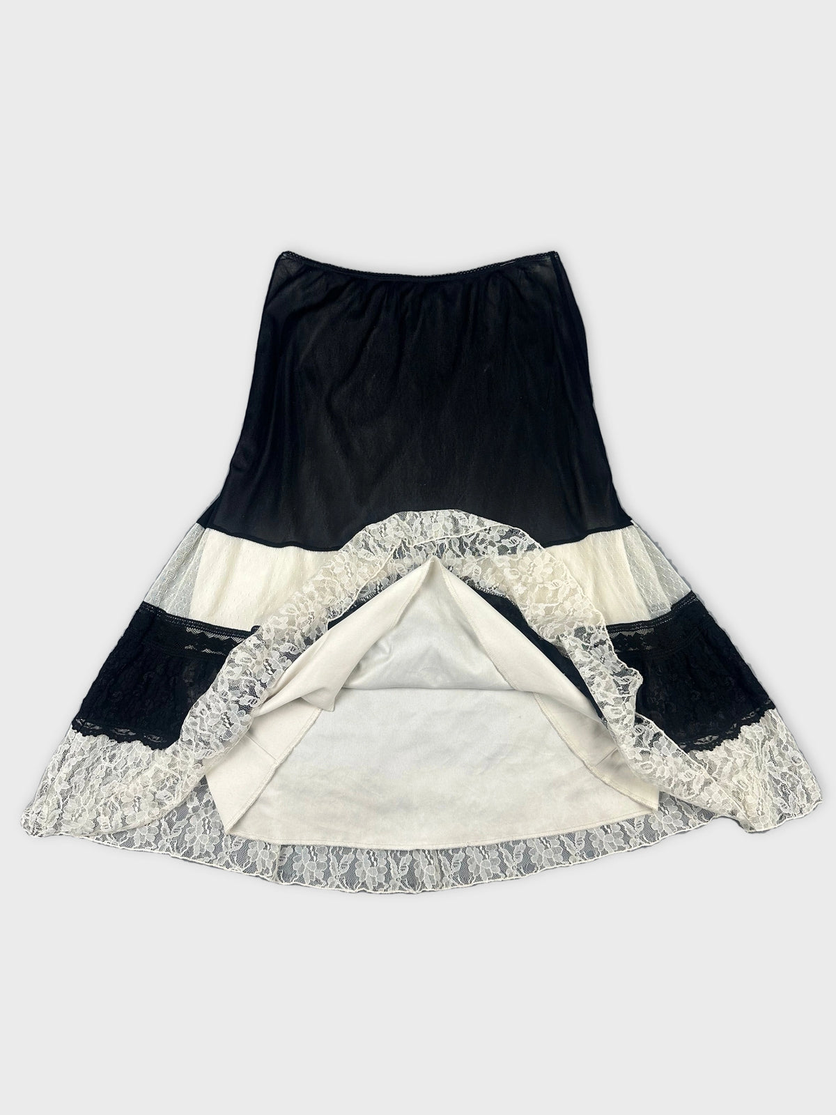 Detail view of a black and white skirt featuring lace trim and a flared shape.