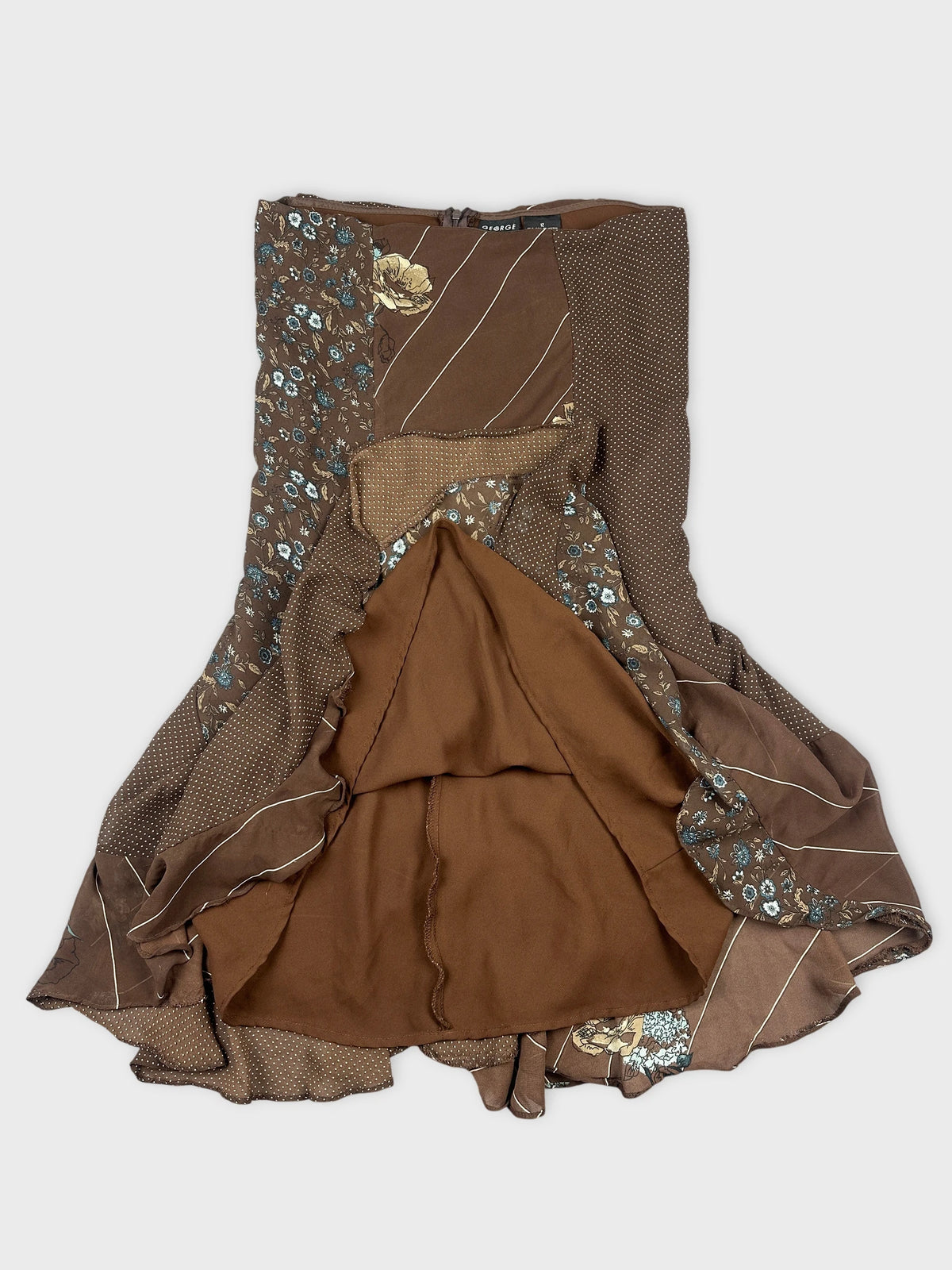 Detail view of a brown patterned skirt featuring floral prints and ruffled hem.