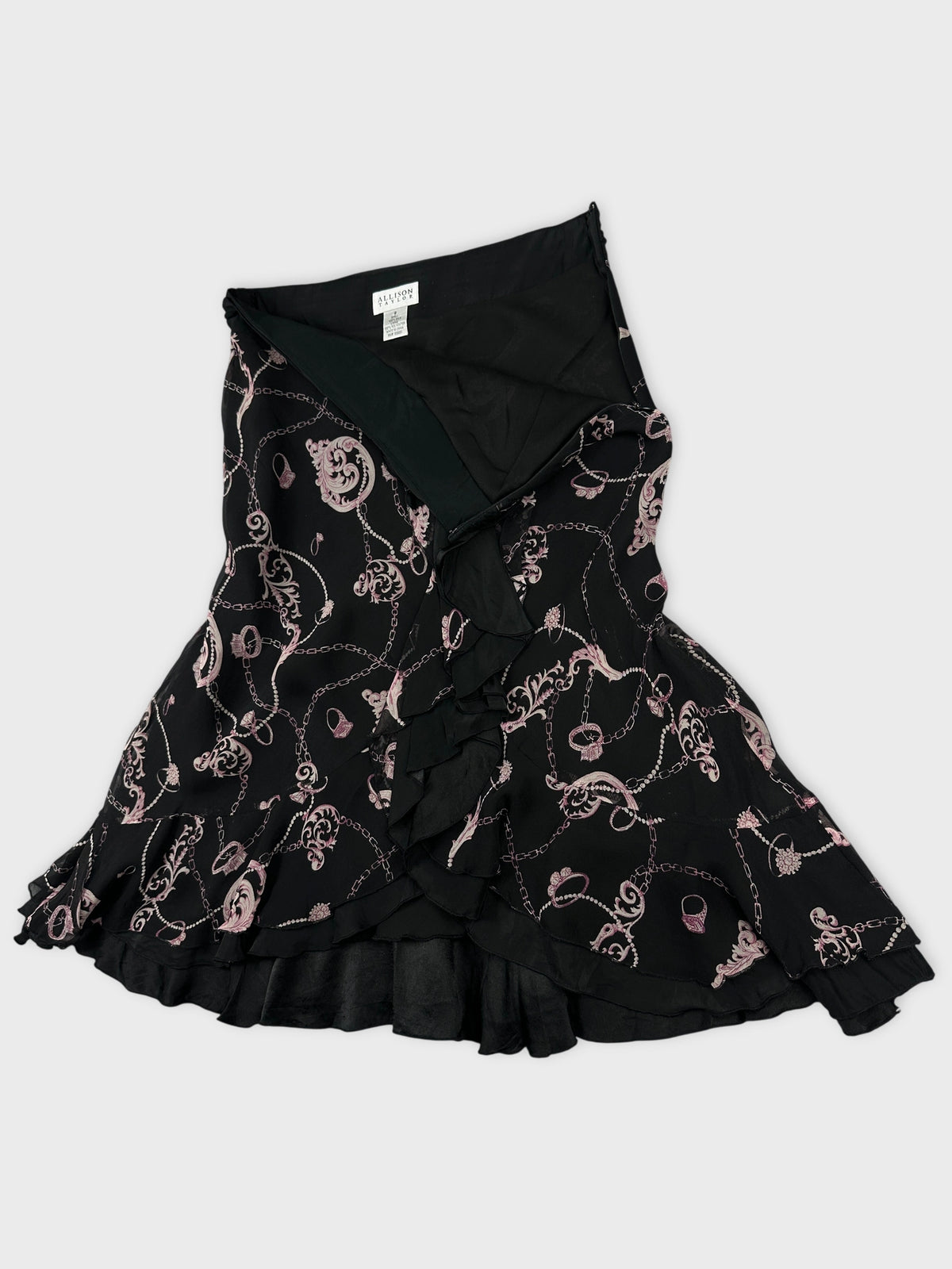 Detail view of a black skirt with pink floral print and ruffled hem.
