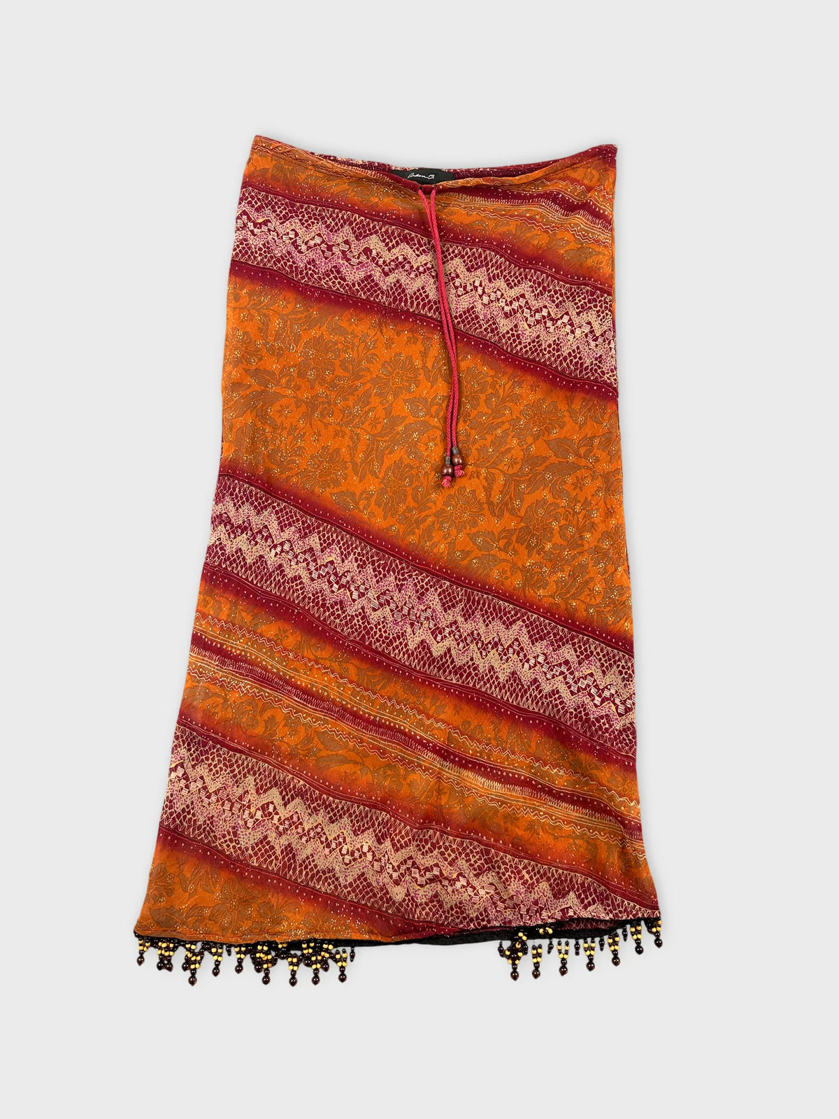 Front view of a vintage orange skirt with decorative beaded trim.