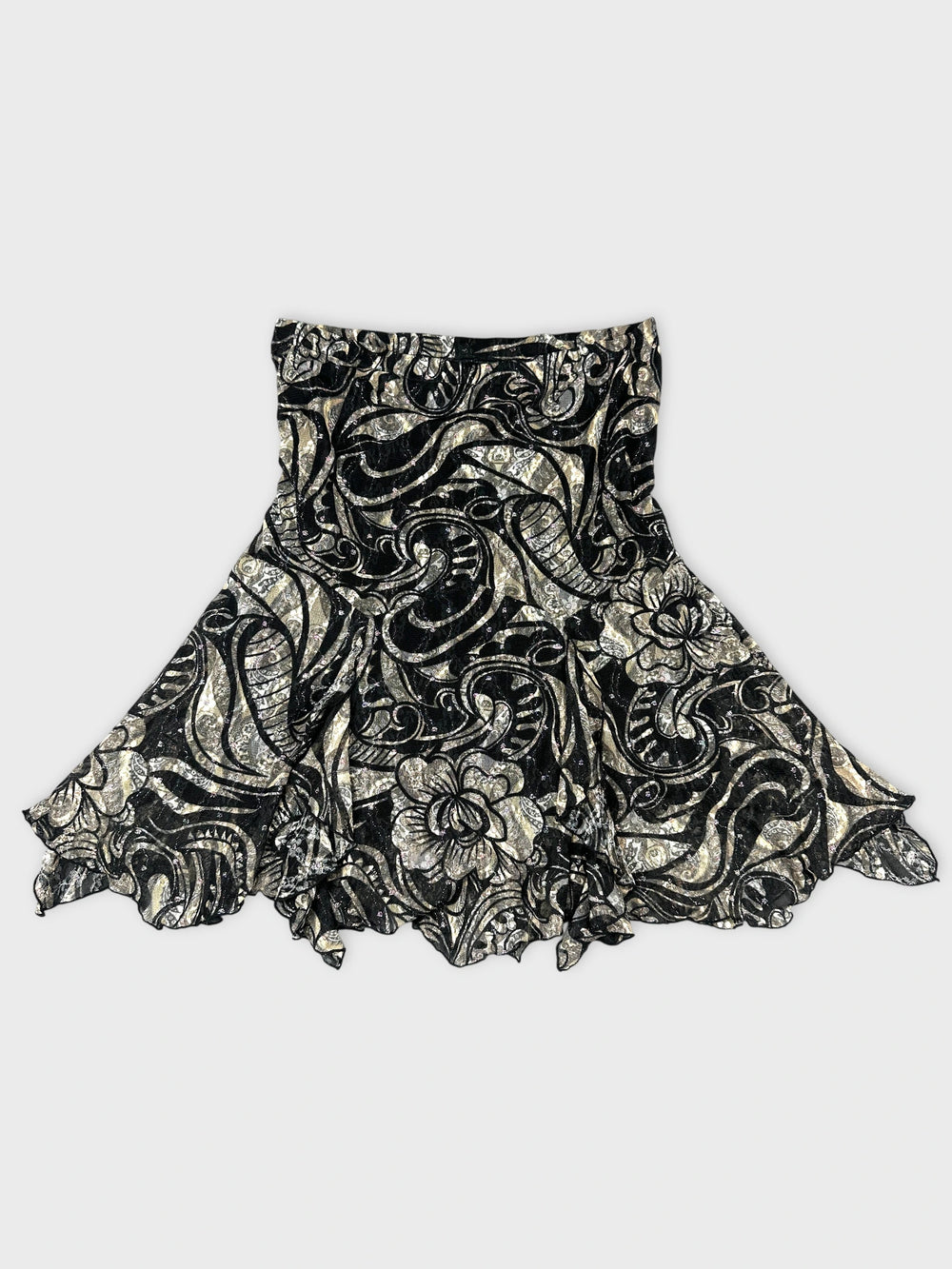 Front view of a black skirt with silver floral pattern and ruffled hem.