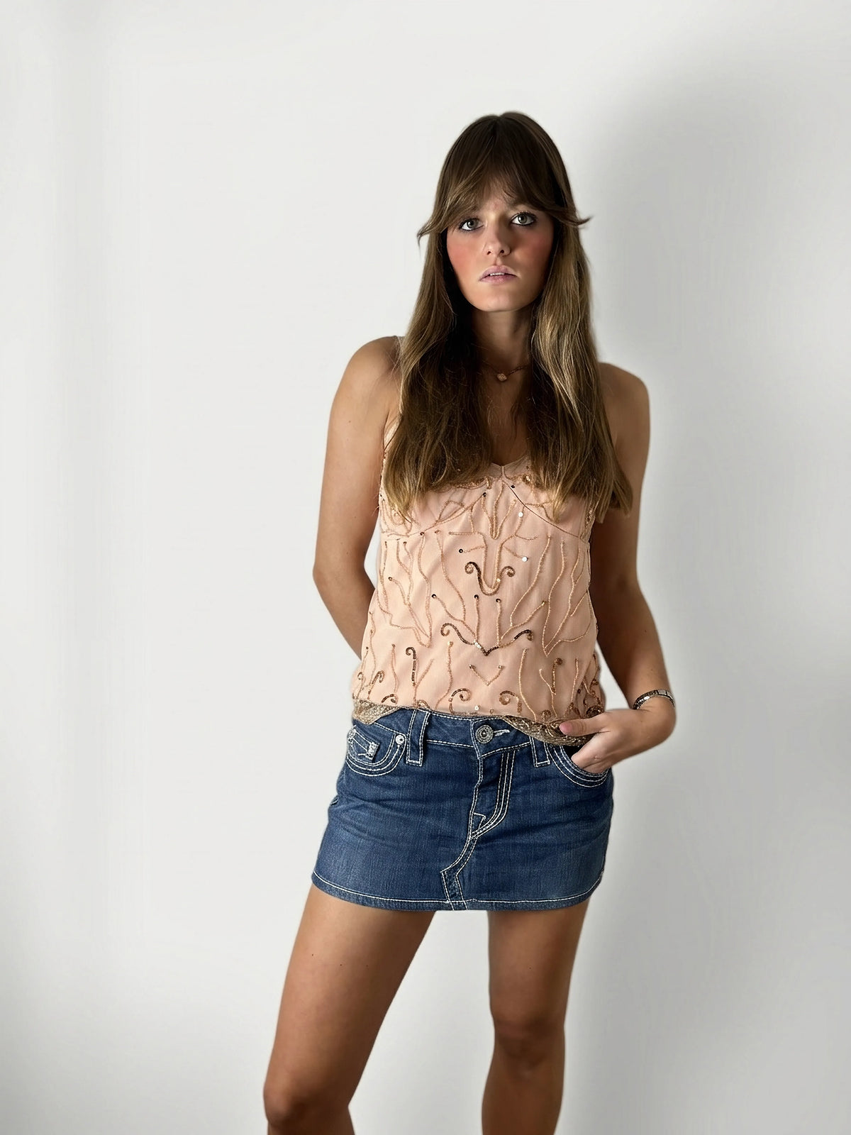 Front view of a blue denim mini skirt with gold stitching details.