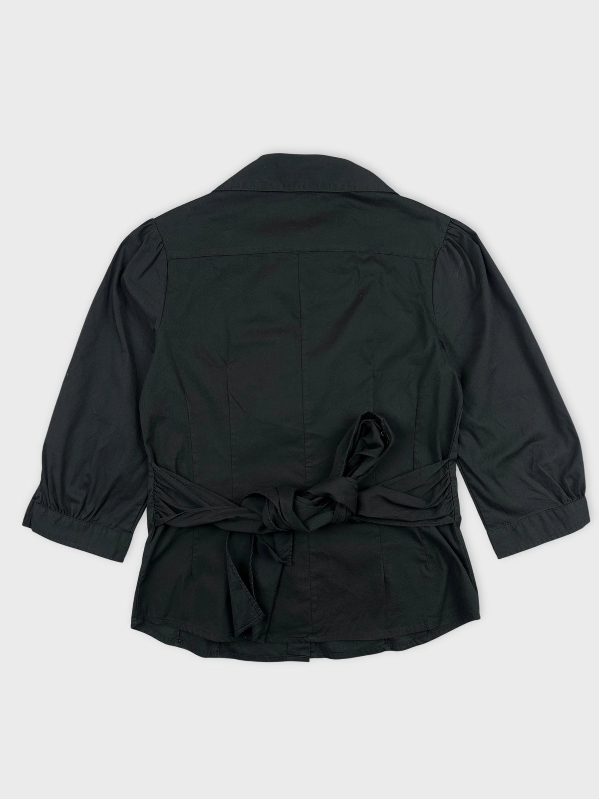 Back view of a black vintage women’s shirt with a tied waist detail.