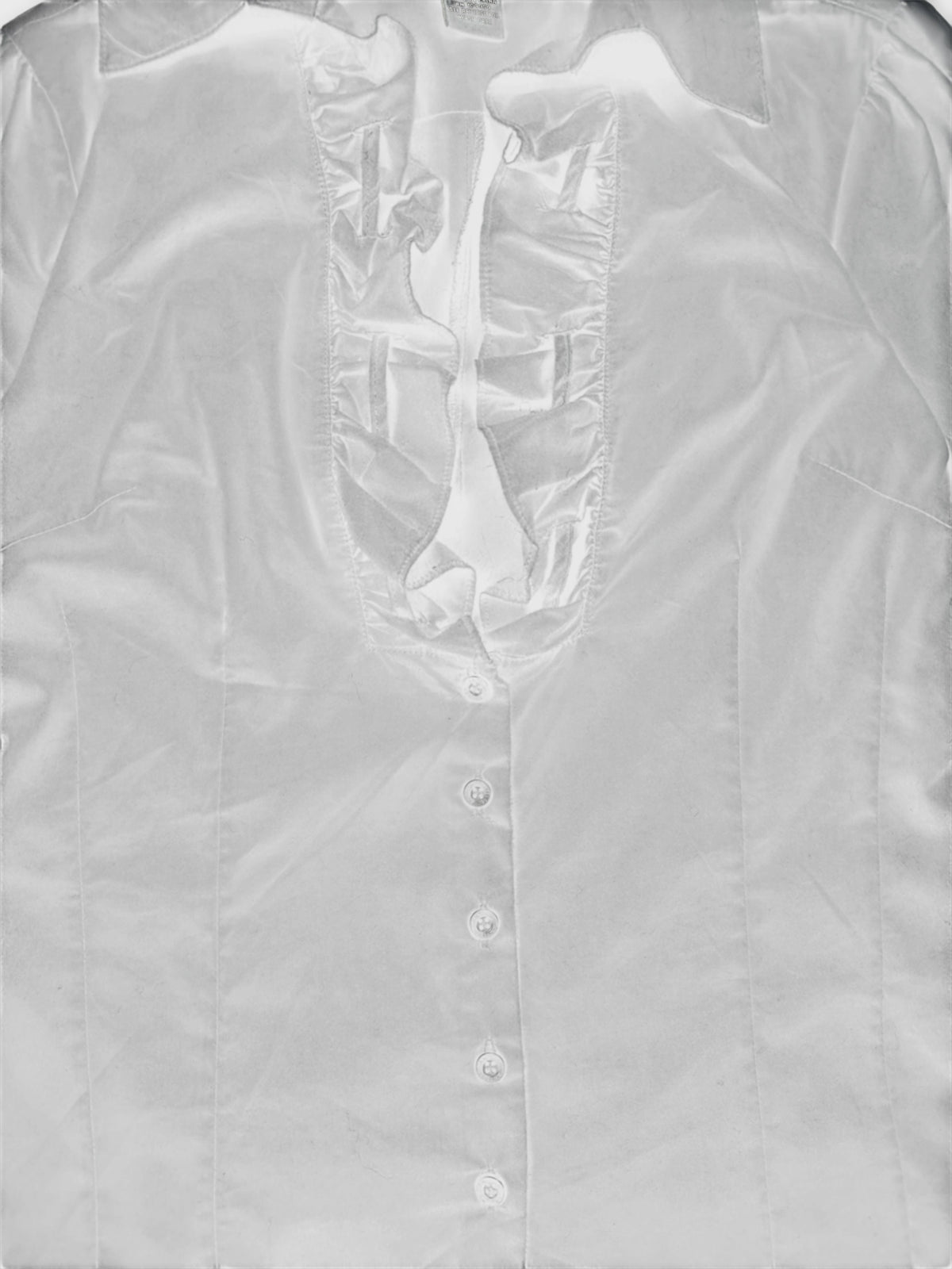 Detail view of a white women's shirt with a ruffled neckline.