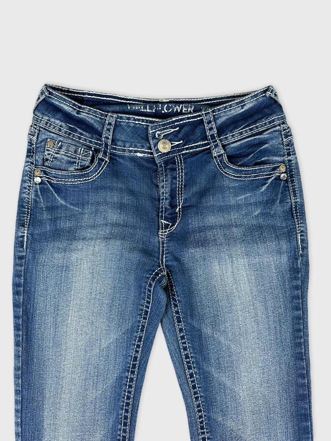 Detail view of wide jeans in blue with contrast stitching and decorative buttons.