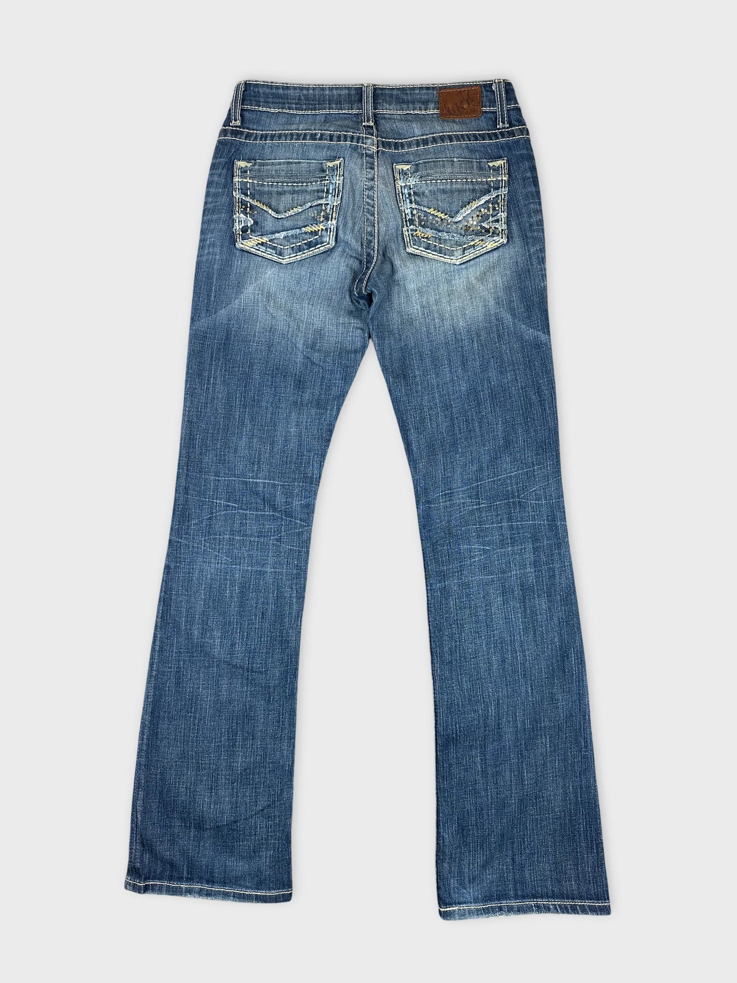 Back view of blue denim jeans featuring embroidered pockets and flared legs.