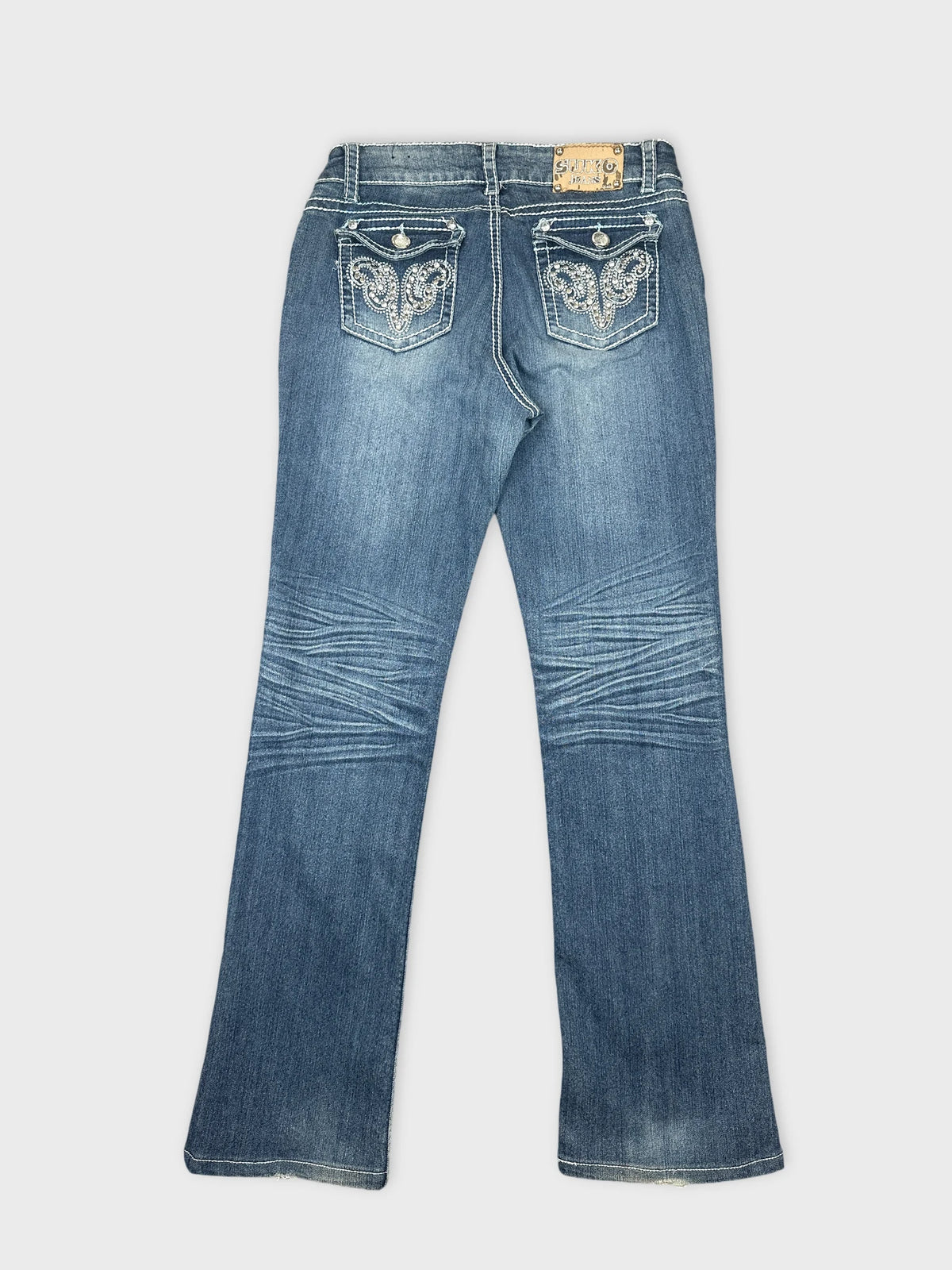 Back view of blue denim jeans featuring decorative pockets and a flared shape.