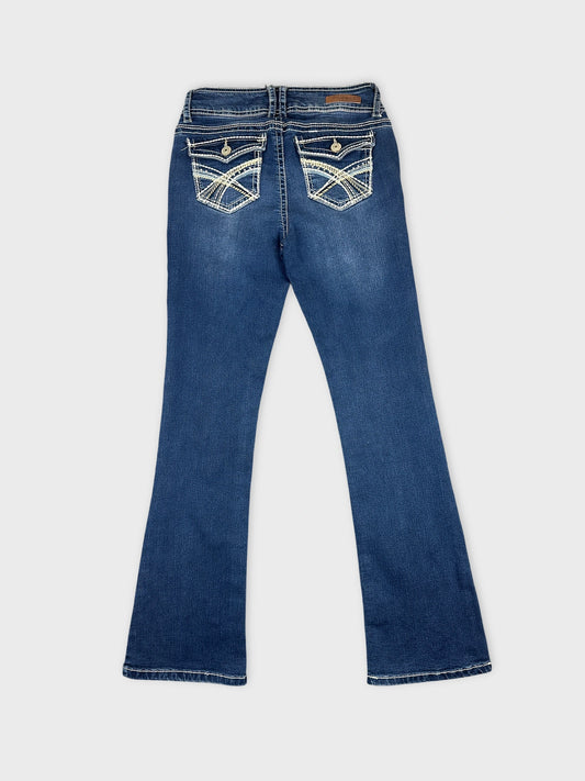 Back view of women denim jeans in deep blue with detailed pockets.