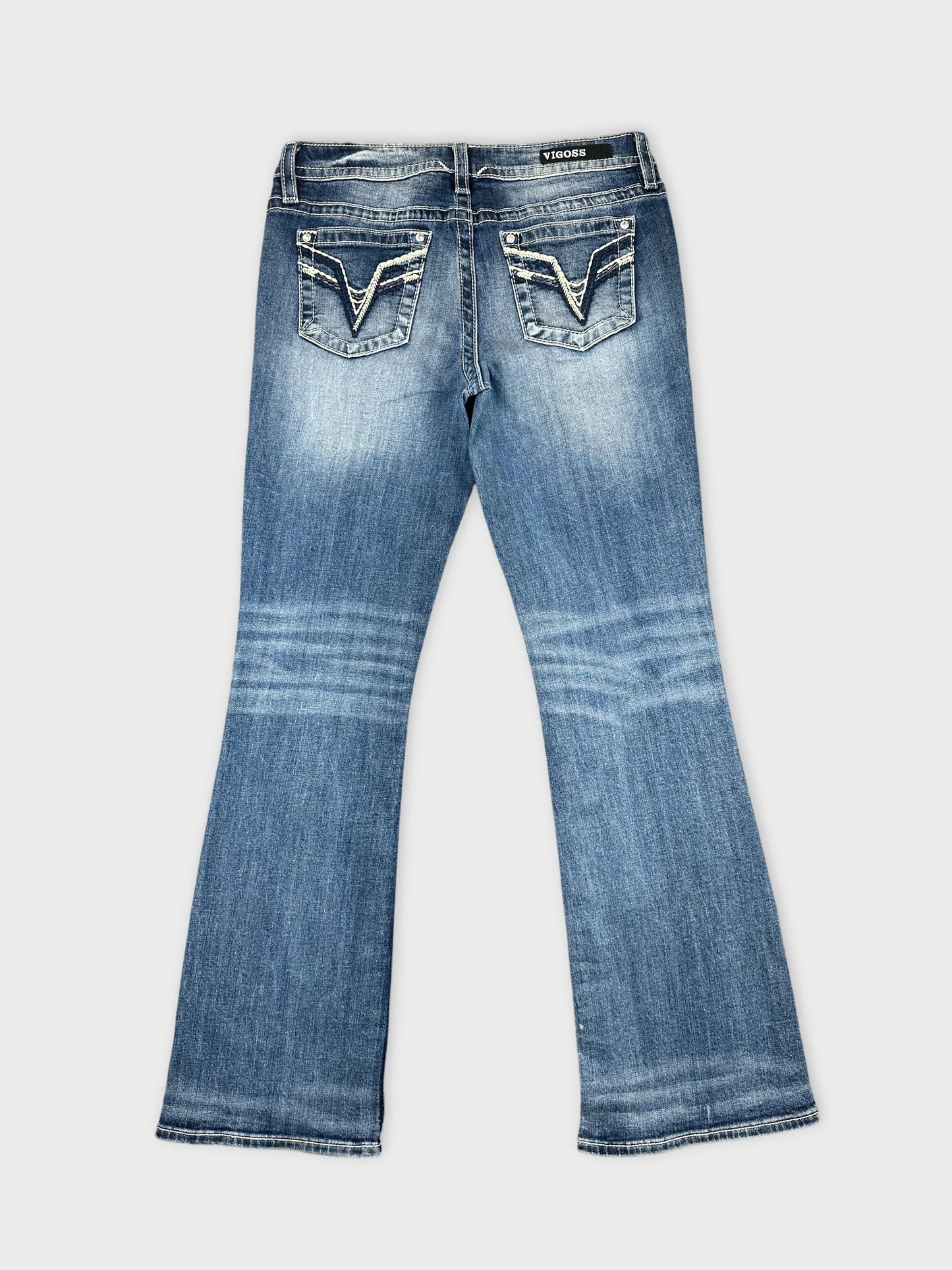 Back view of blue denim jeans with decorative back pockets.