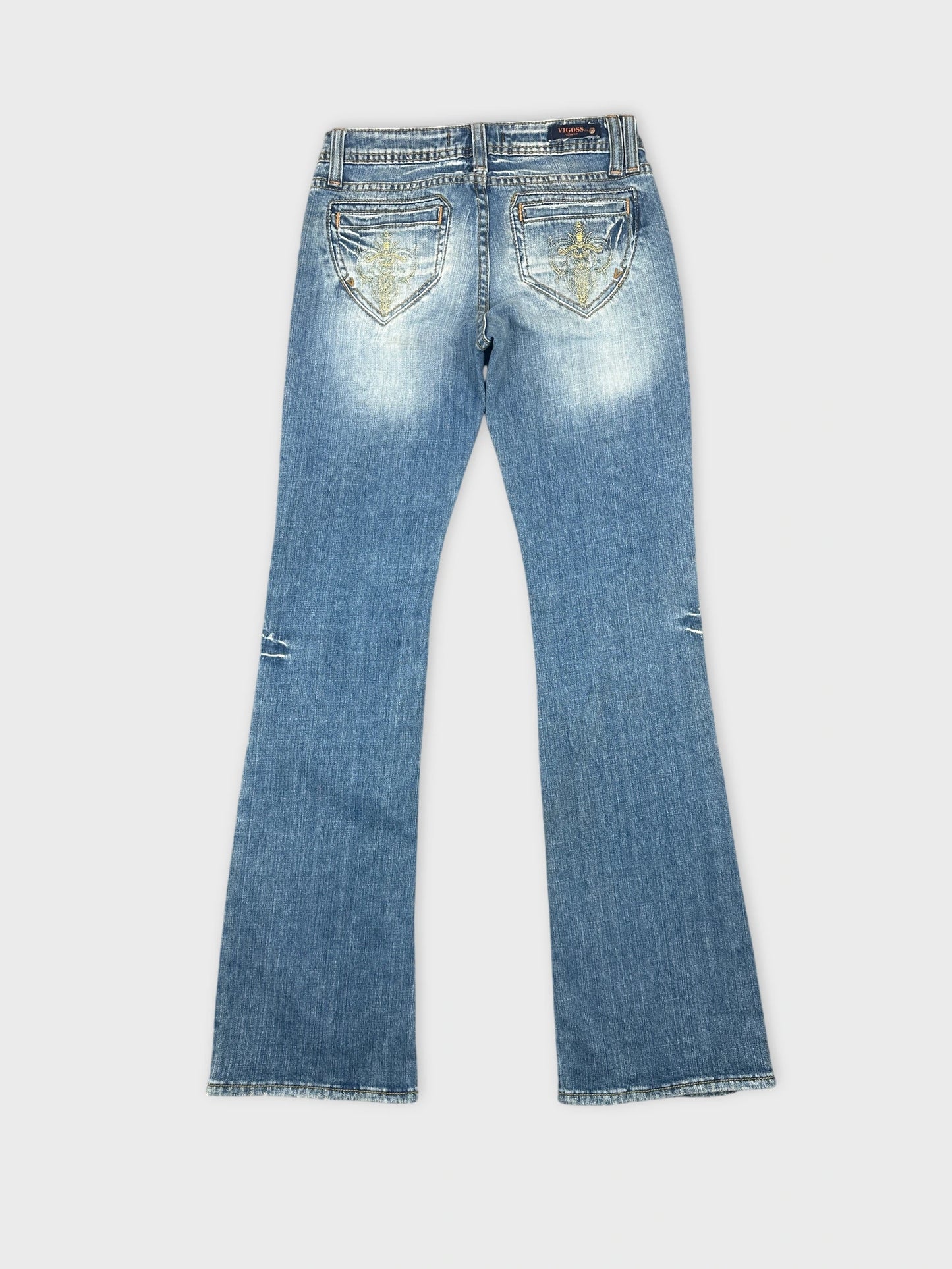 Back view of blue denim jeans featuring embellished pockets and flare leg.