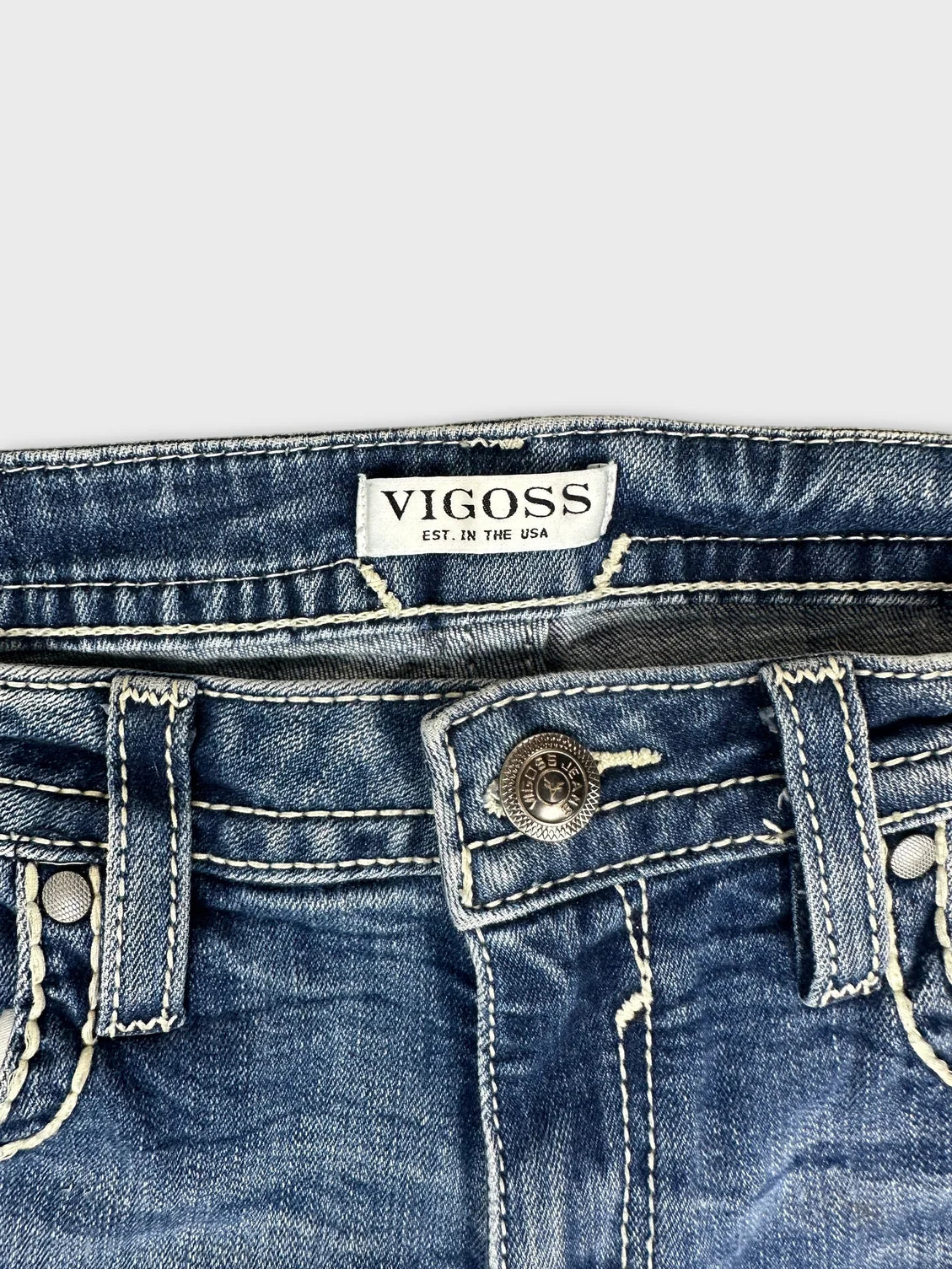 Detail view of denim jeans with a blue color and prominent stitching.