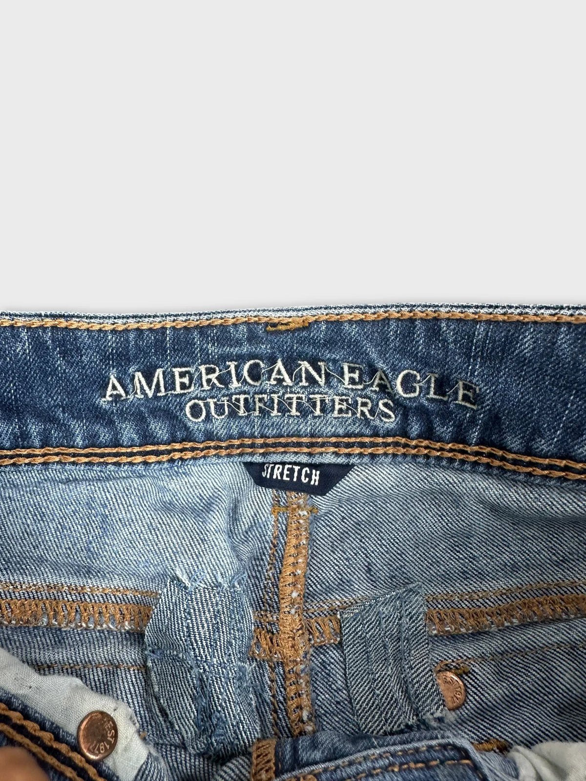Detail view of women denim jeans in light blue with stitched logo.