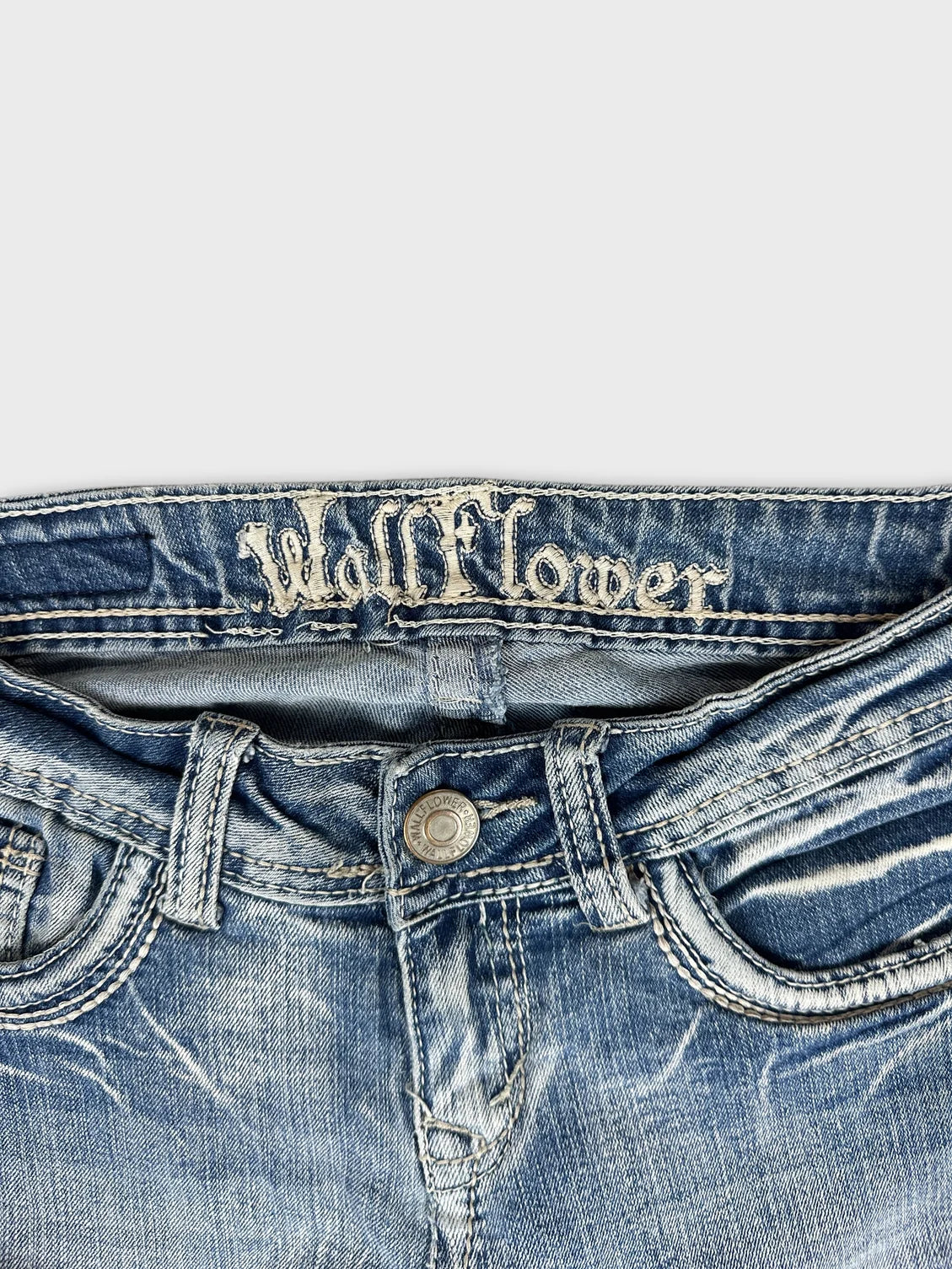 Detail view of blue denim jeans showcasing vintage branding and stitching.
